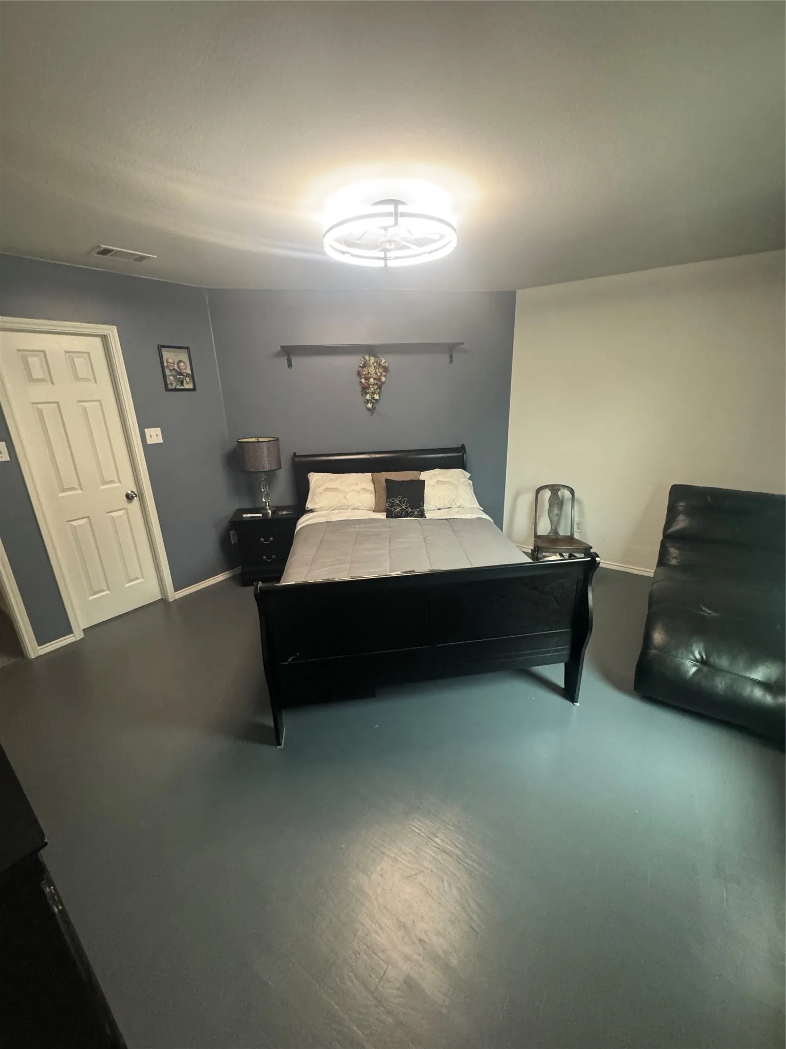 Spacious room featuring a white paneled door, two-tone wall paint, a modern flush mount ceiling light, and durable hard-surface flooring