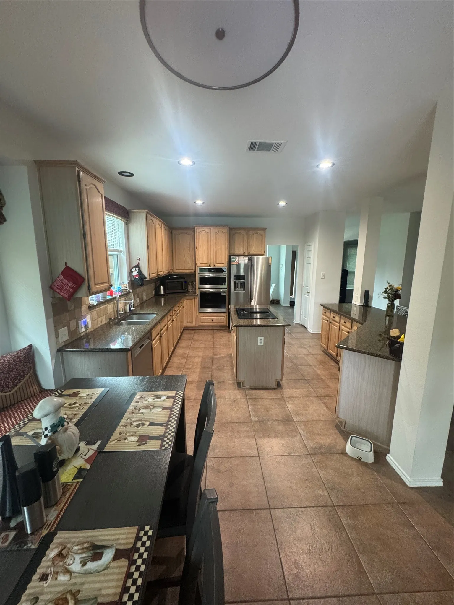 Spacious kitchen featuring wood-finish cabinetry, dark countertops, and tile flooring