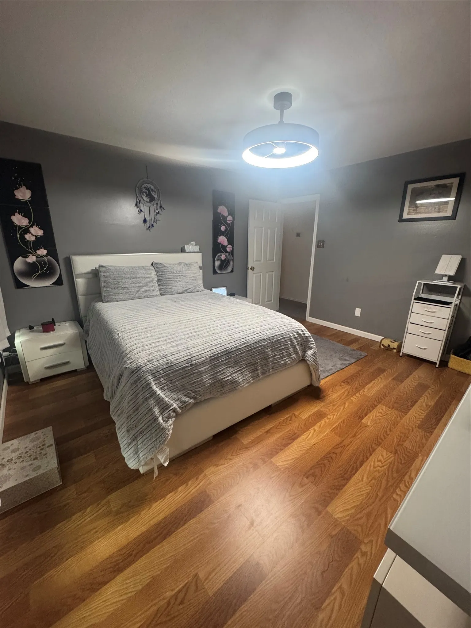 Room featuring wood-finish flooring, neutral wall tones, and a contemporary ceiling light fixture