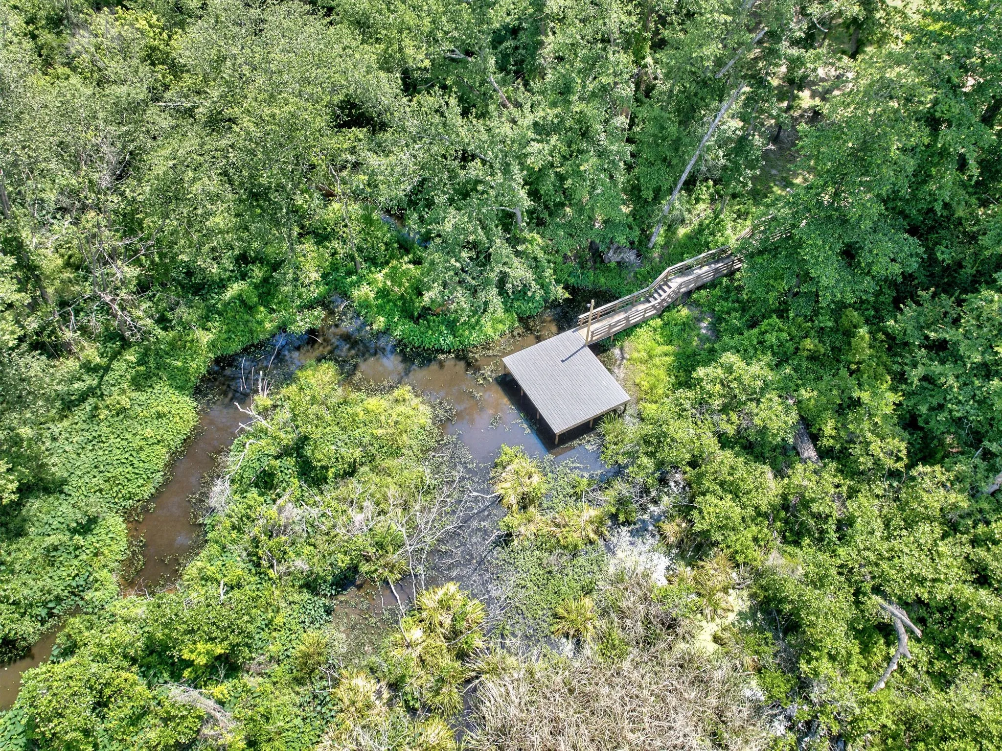 Dock structure with a covered boat slip, accessed by a wooden walkway