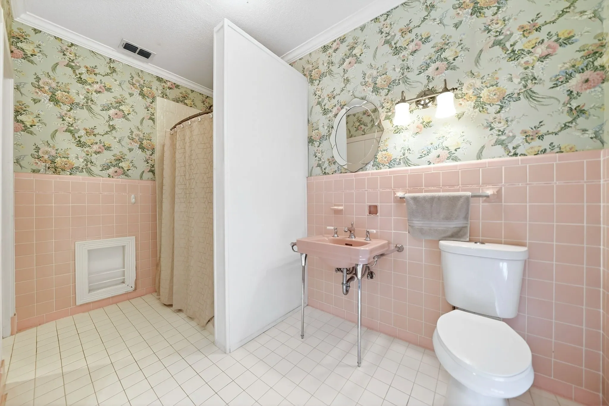 Bathroom featuring white square floor tiling, pink square wall tiling, and floral wallpaper