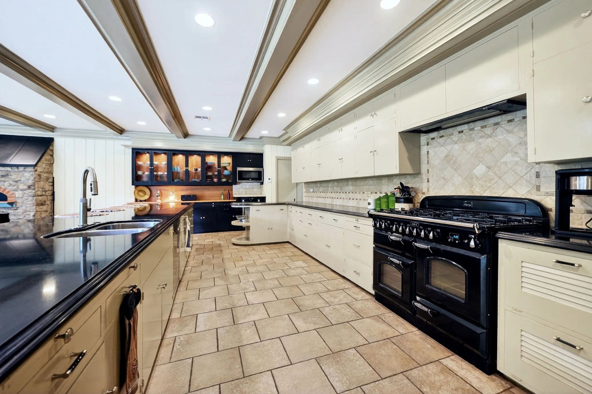 Spacious kitchen featuring a large black range, extensive cabinetry, recessed lighting, and a stone pizza oven