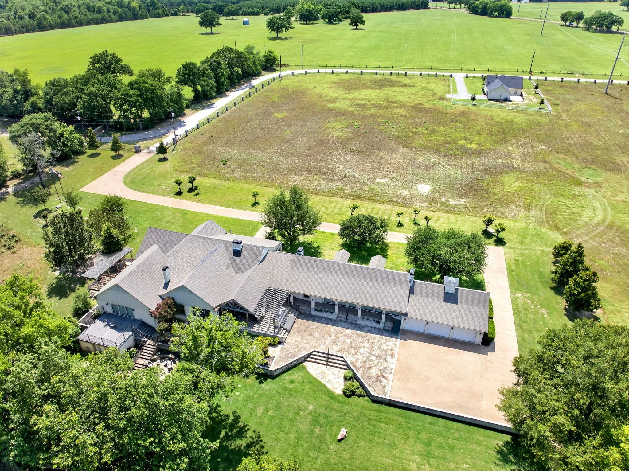 Expansive property featuring a large residence with a multi-car garage, extensive paved and stone driveways, and mature landscaping