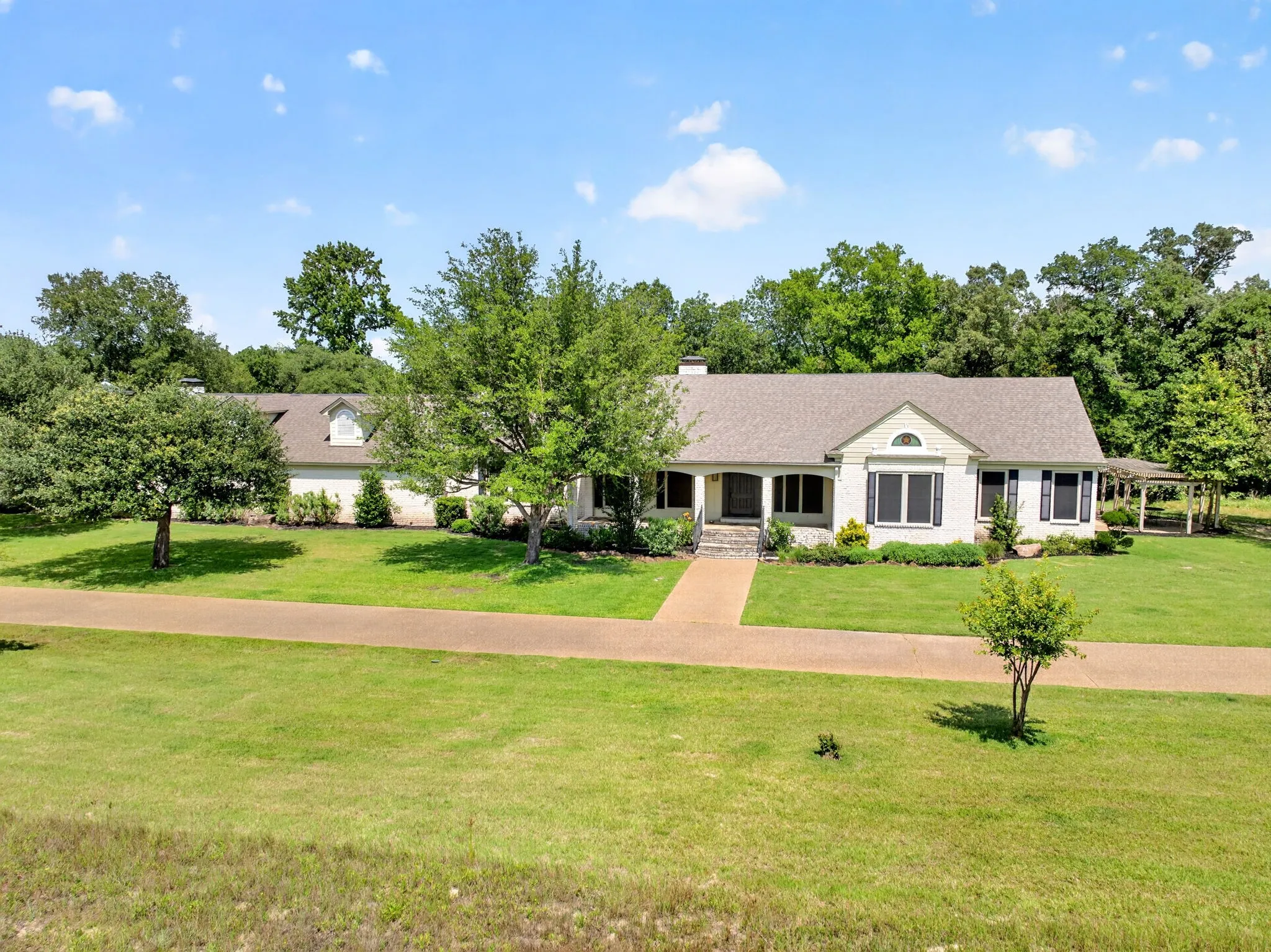 Expansive front yard featuring a long driveway and mature trees