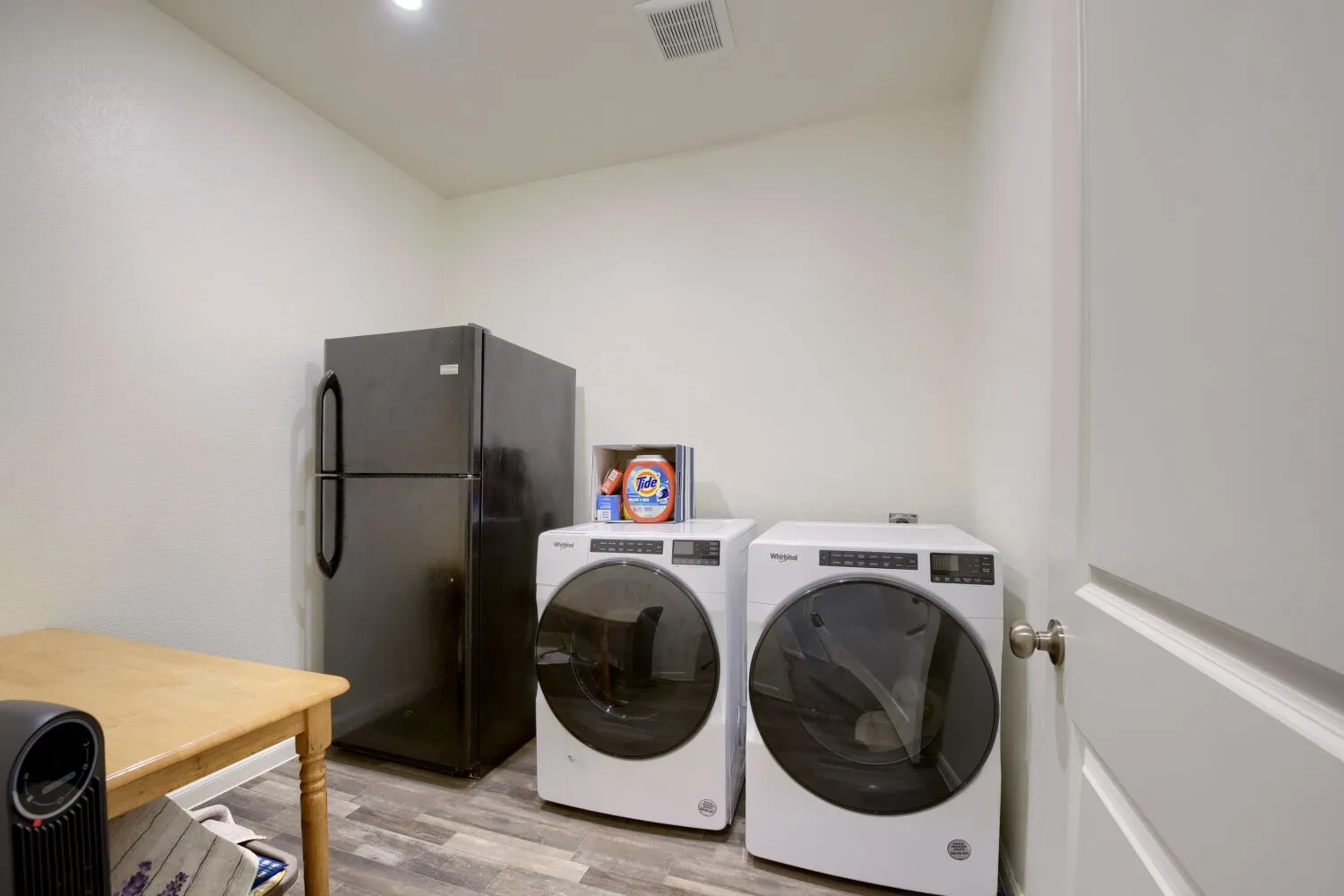 Utility room with wood-finish flooring, recessed lighting, and a white paneled door with a brushed nickel knob