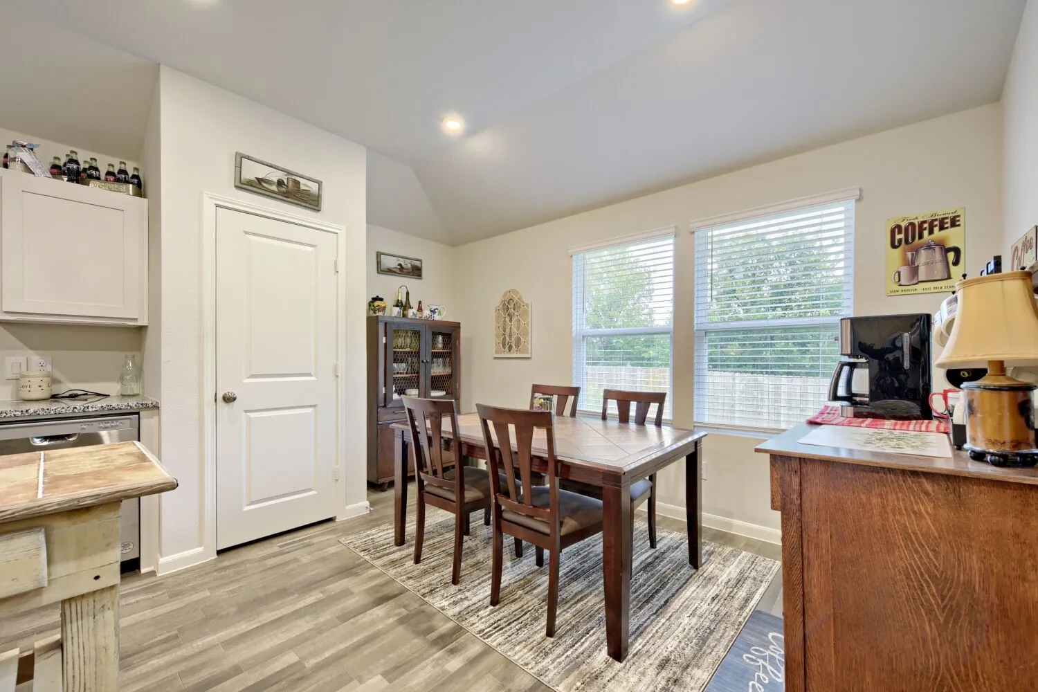 Dining area featuring wood-finish flooring, two window openings with blinds, and recessed lighting