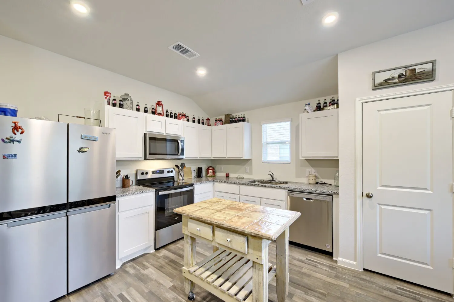Kitchen featuring white cabinetry, light-toned countertops, wood-finish flooring, stainless steel appliances, and recessed lighting