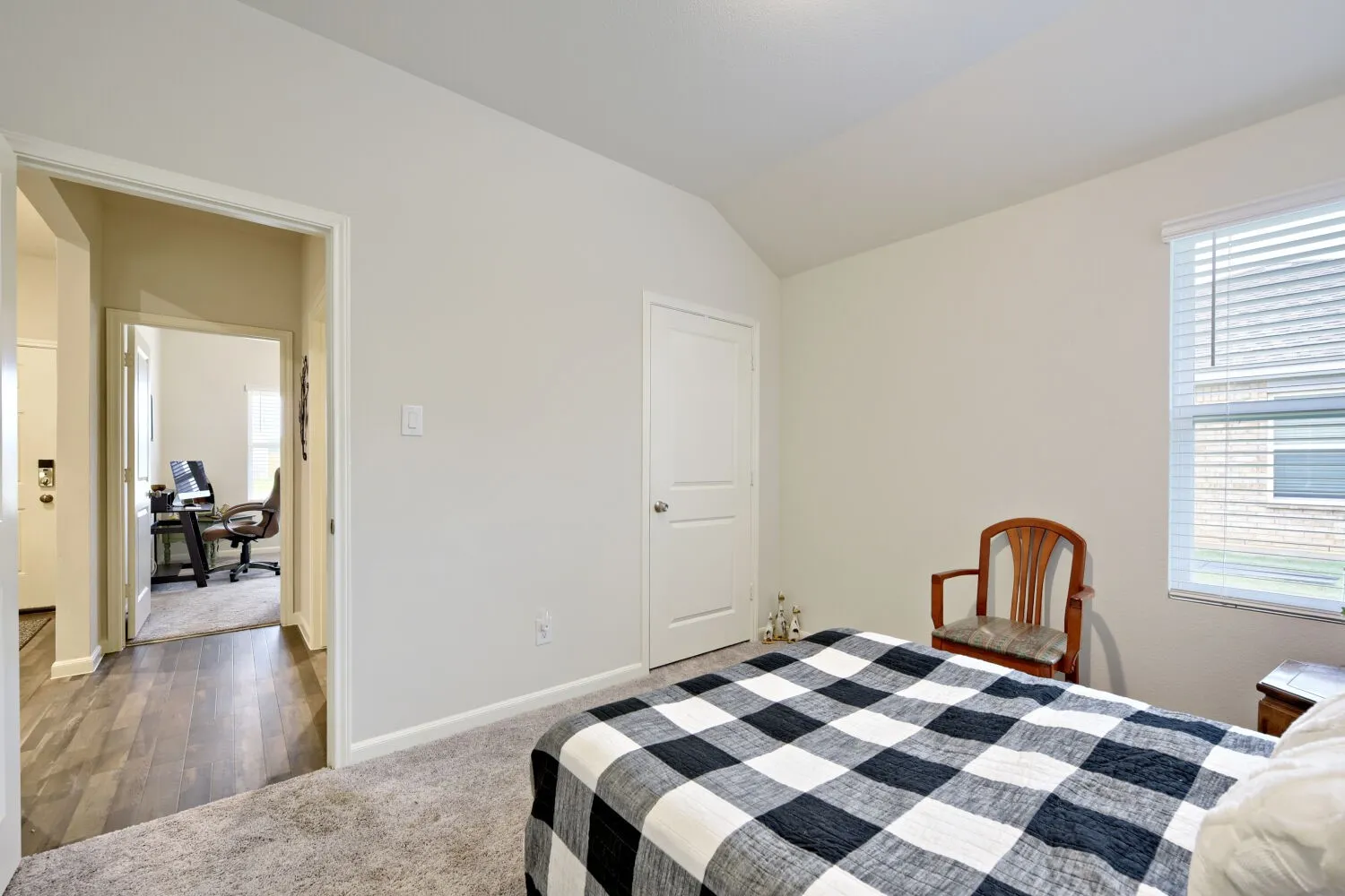 Carpeted room with a vaulted ceiling and a window featuring horizontal blinds