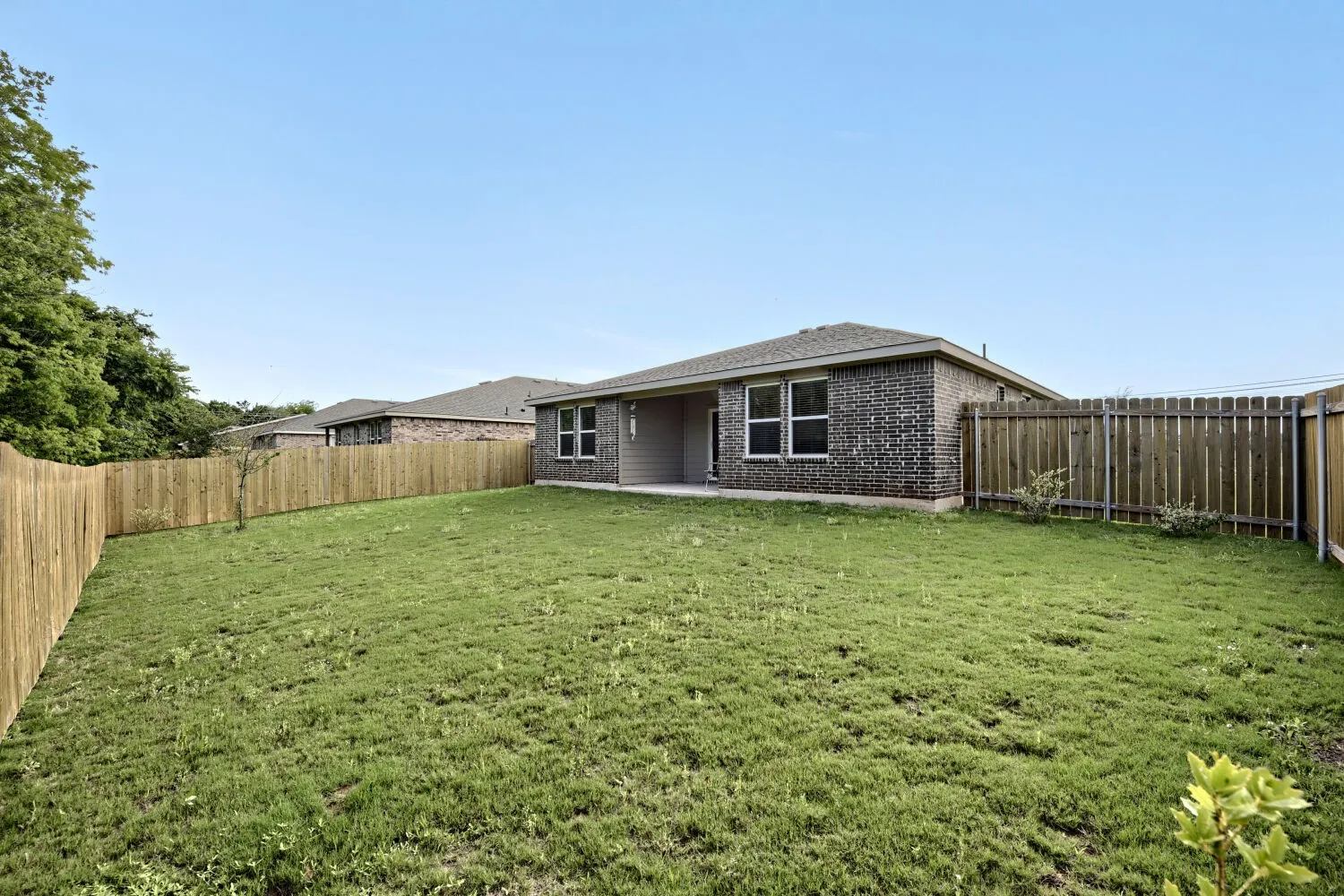 Expansive grass lawn bordered by a wood privacy fence