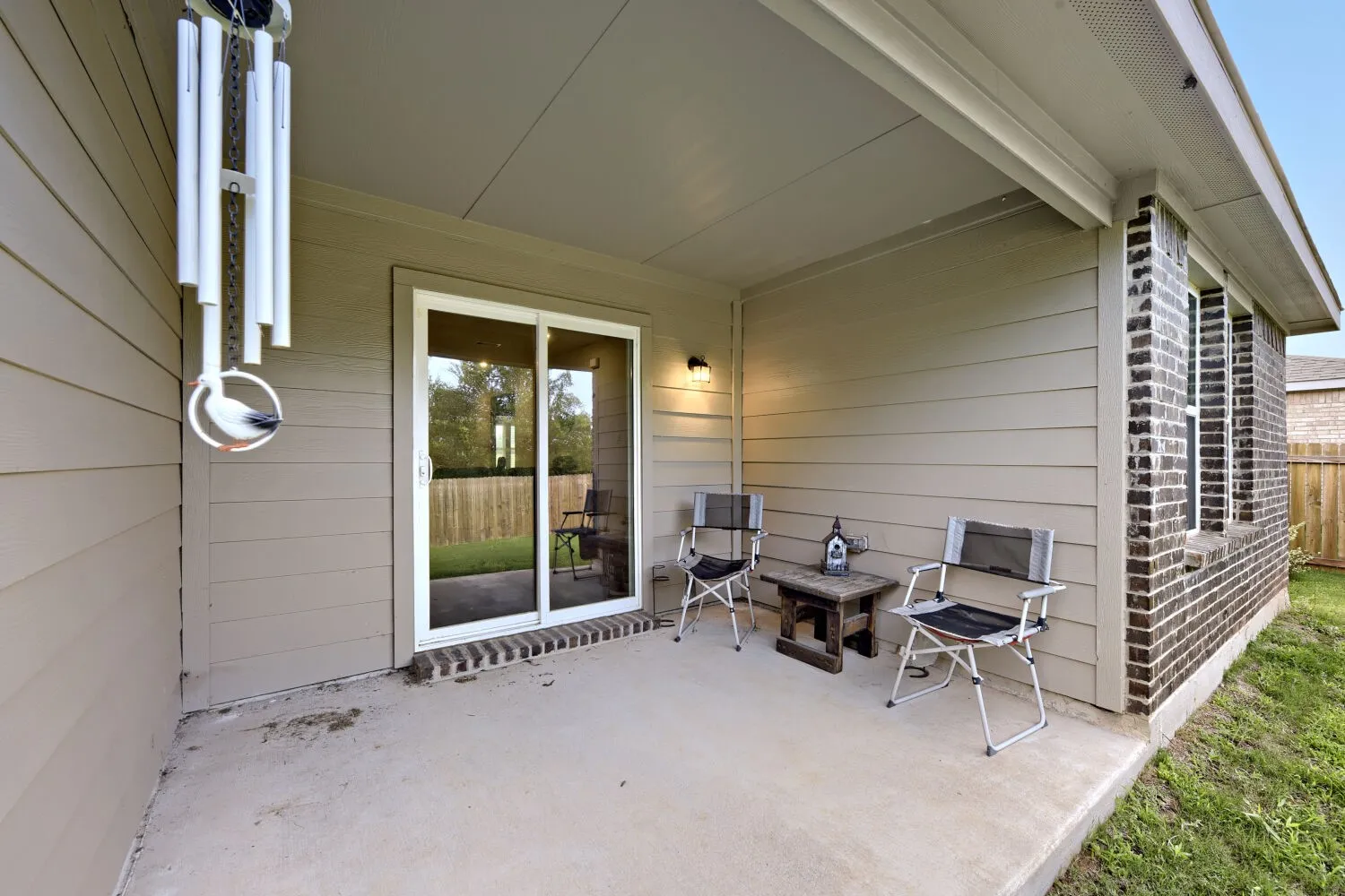 Covered concrete patio featuring a sliding glass door entry, exterior wall sconce, and horizontal siding