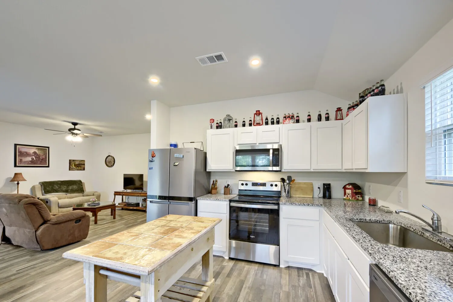 Kitchen featuring white cabinetry, stainless steel appliances, granite-style countertops, and wood-finish flooring