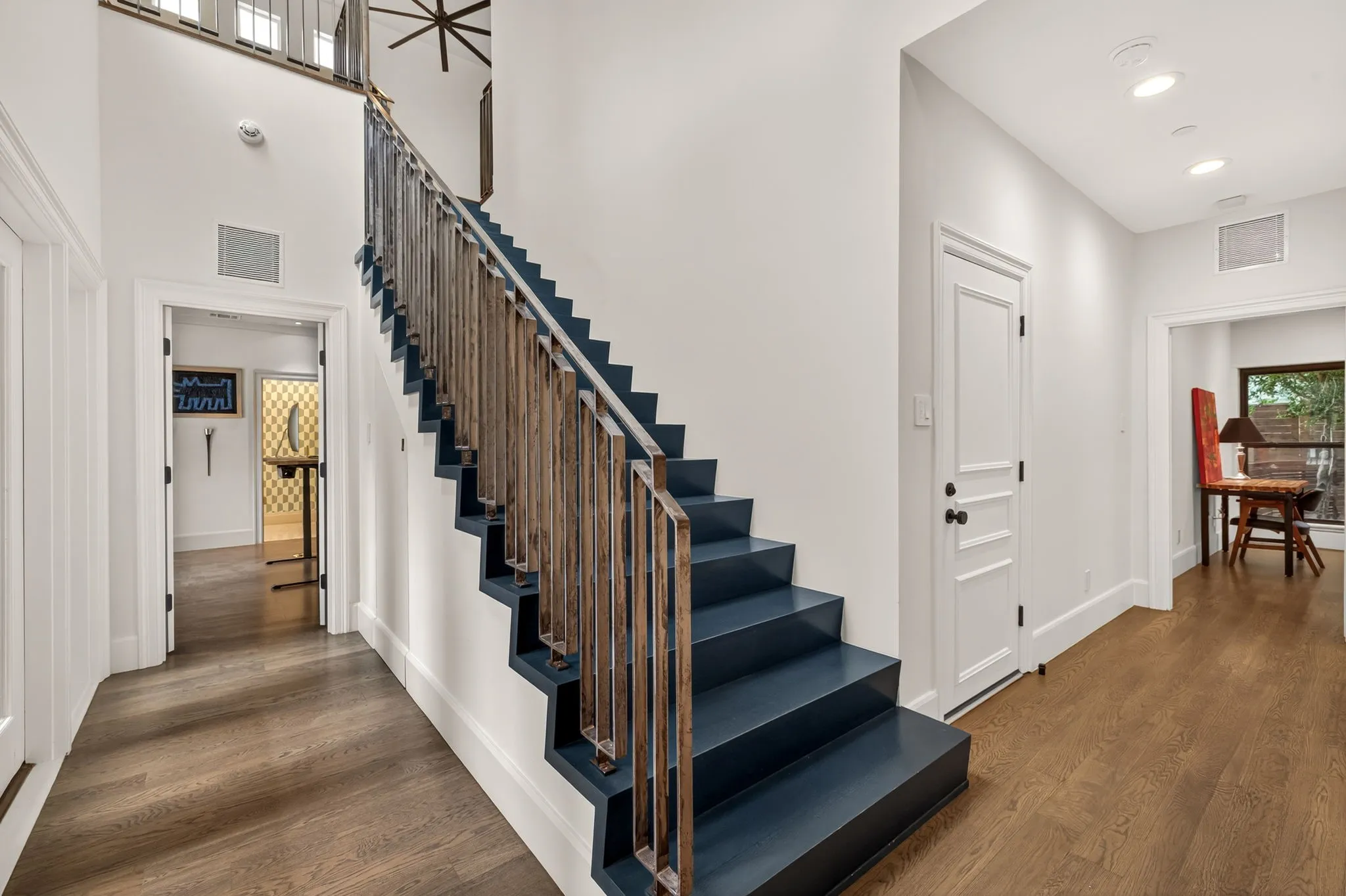 Central staircase featuring contrasting deep blue treads and risers with a vertical wood-finish spindle railing
