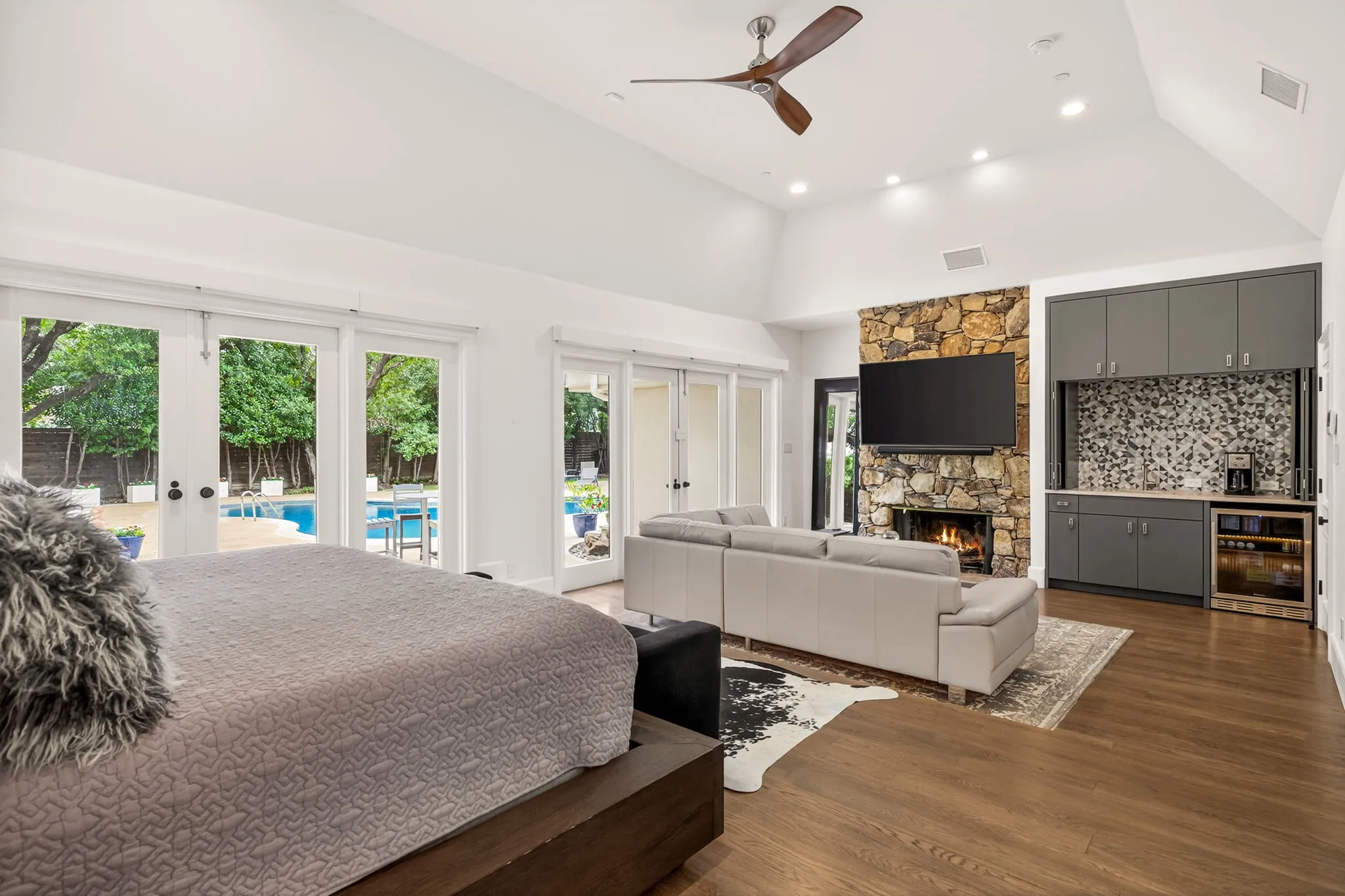 Spacious room featuring vaulted ceilings, wood-finish flooring, and a stone-clad fireplace