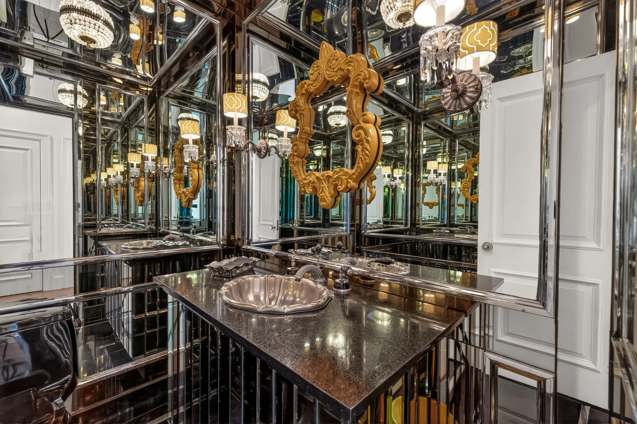 Vanity area featuring an ornate gold-framed mirror and multiple wall-mounted sconces