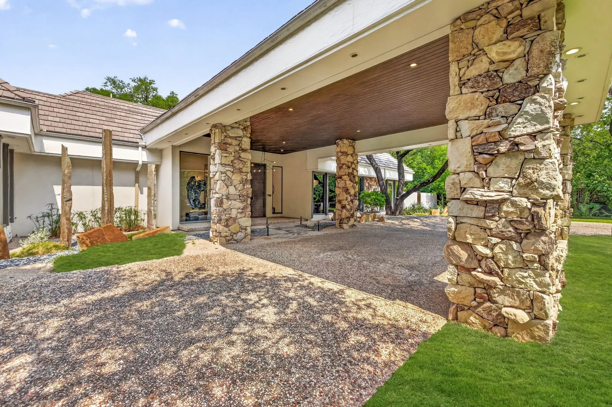 Stone-clad columns and a wood-paneled porte-cochère define the front exterior