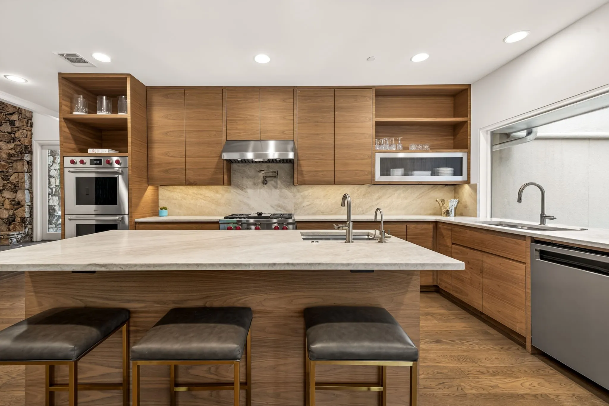 Modern kitchen featuring wood-finish cabinetry, light-toned countertops, and integrated stainless steel appliances