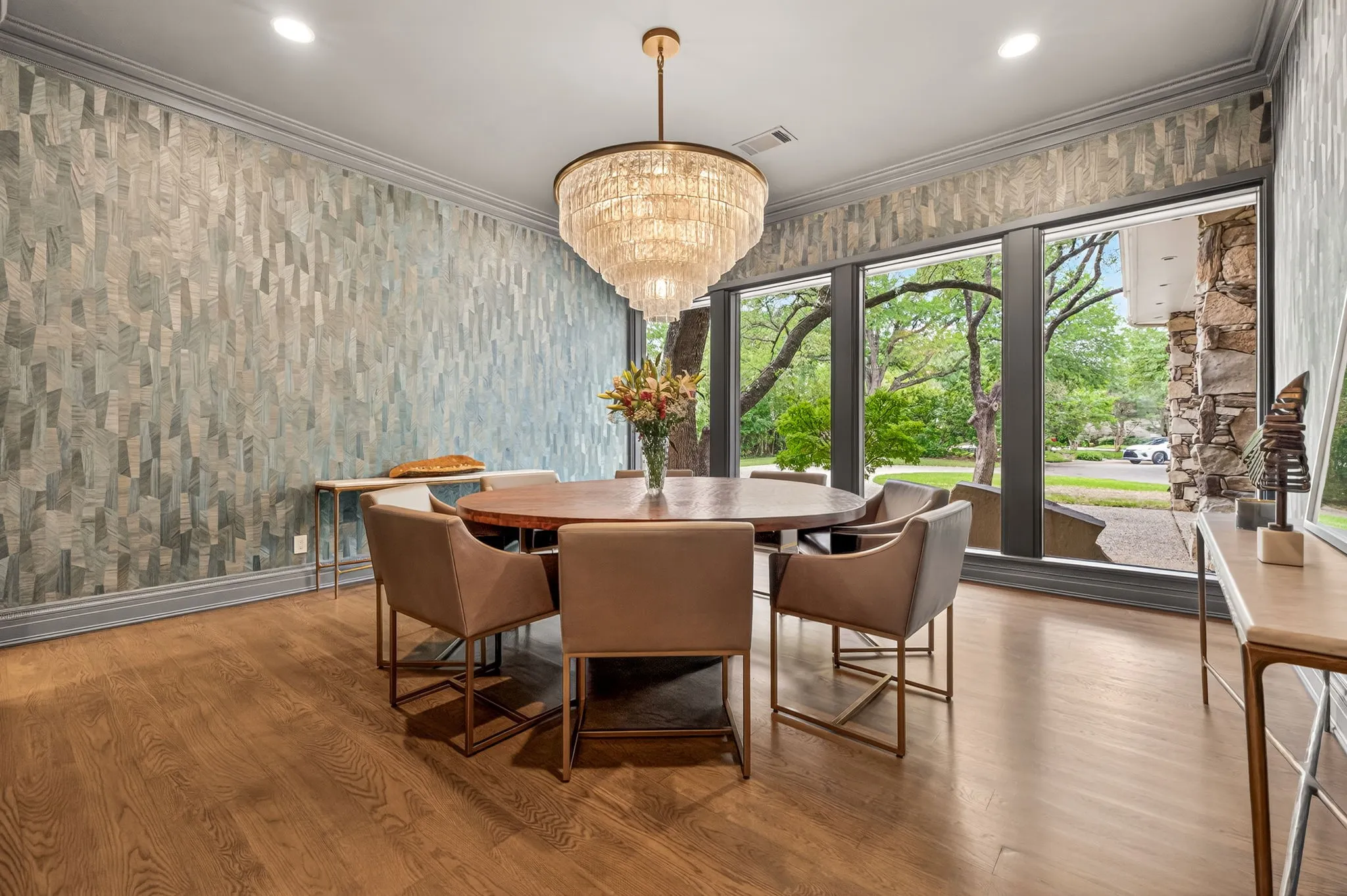 Dining area featuring wood-finish flooring, a large crystal chandelier, full-height windows, and textured wall treatments