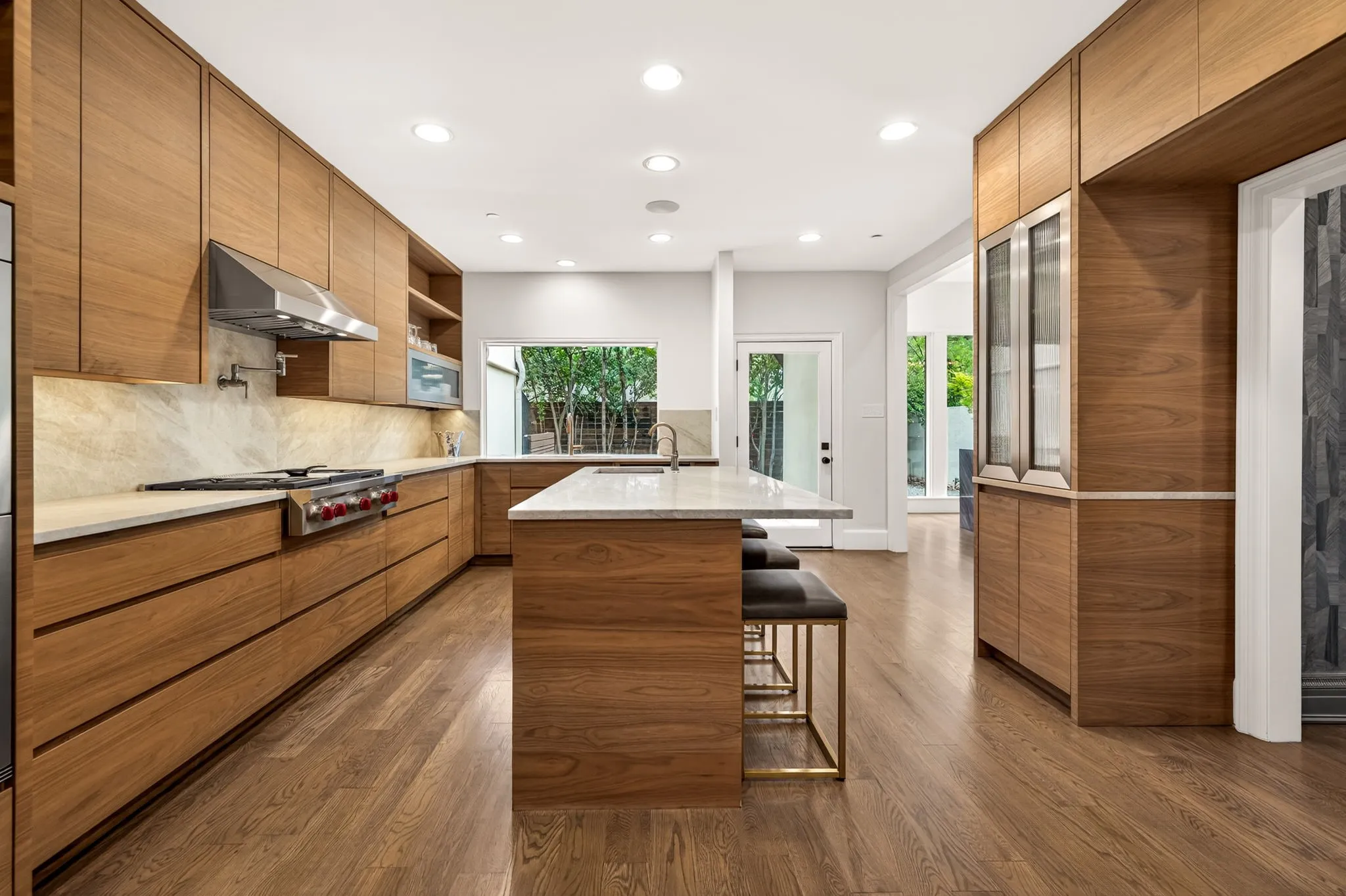 Gourmet kitchen featuring extensive wood-finish cabinetry, light-toned countertops, and a professional-grade range with a stainless steel vent hood