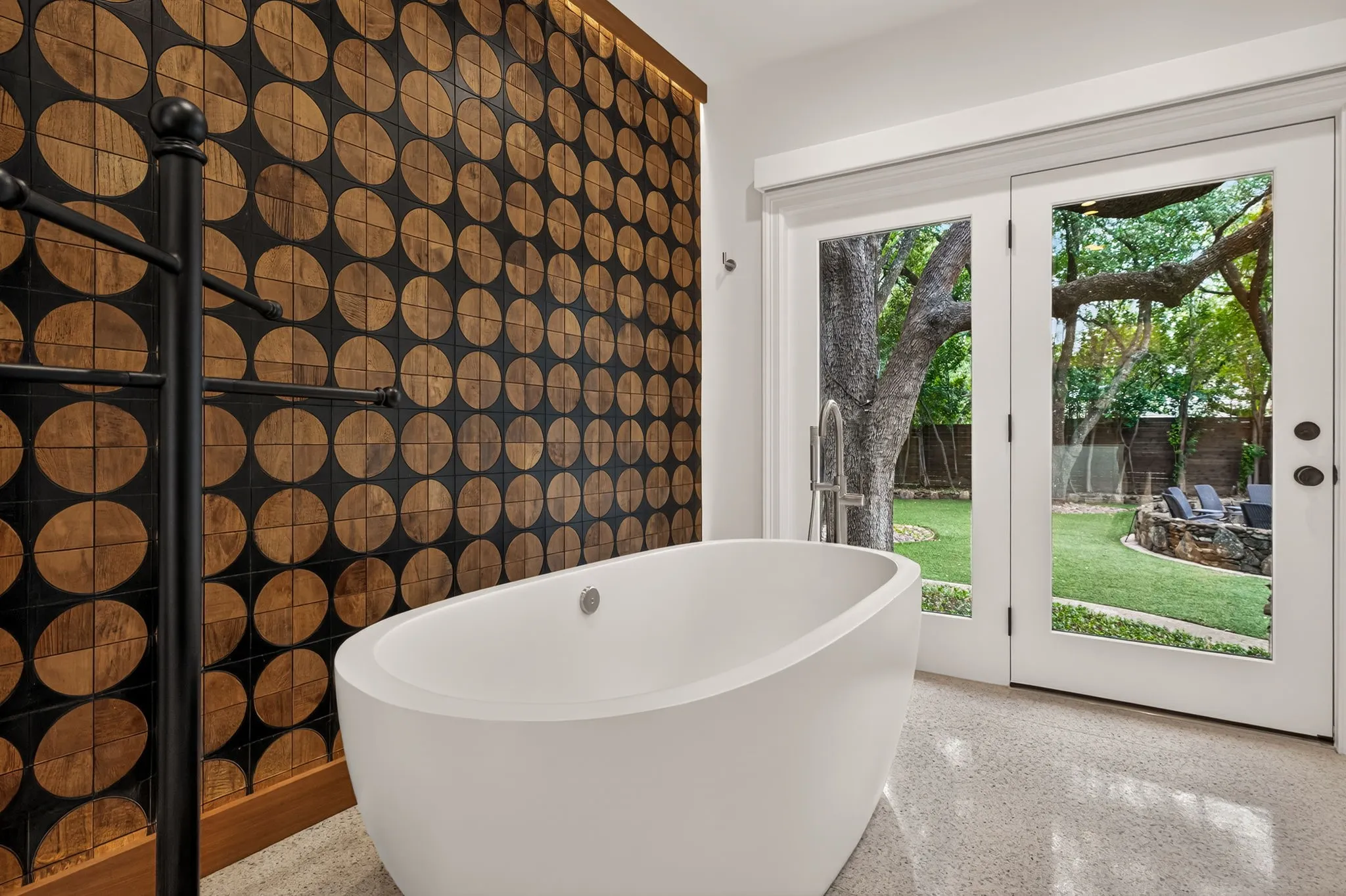 Freestanding soaking tub set against a feature wall with circular wood-finish accents