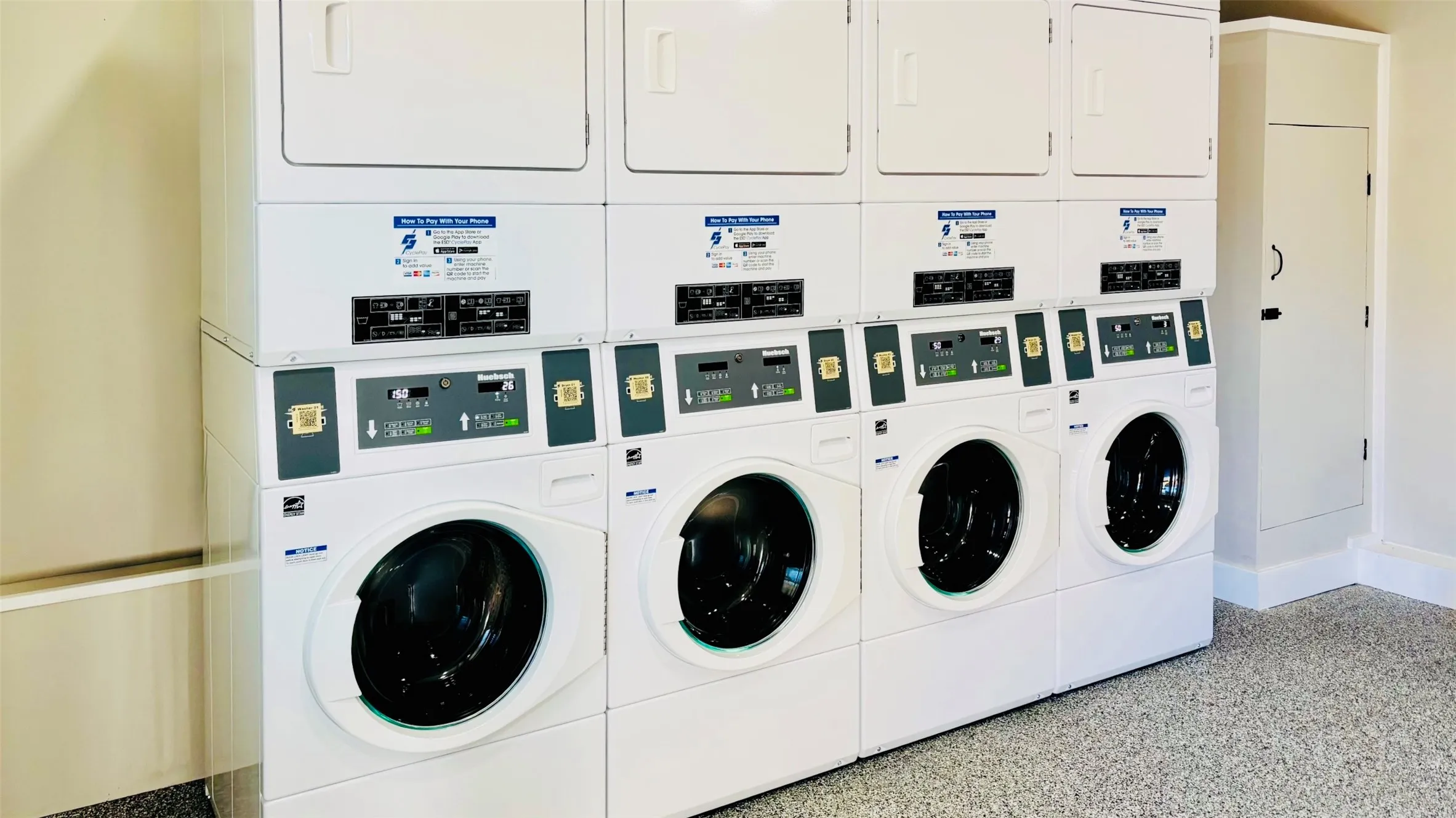 Dedicated laundry area featuring multiple stacked washer and dryer units