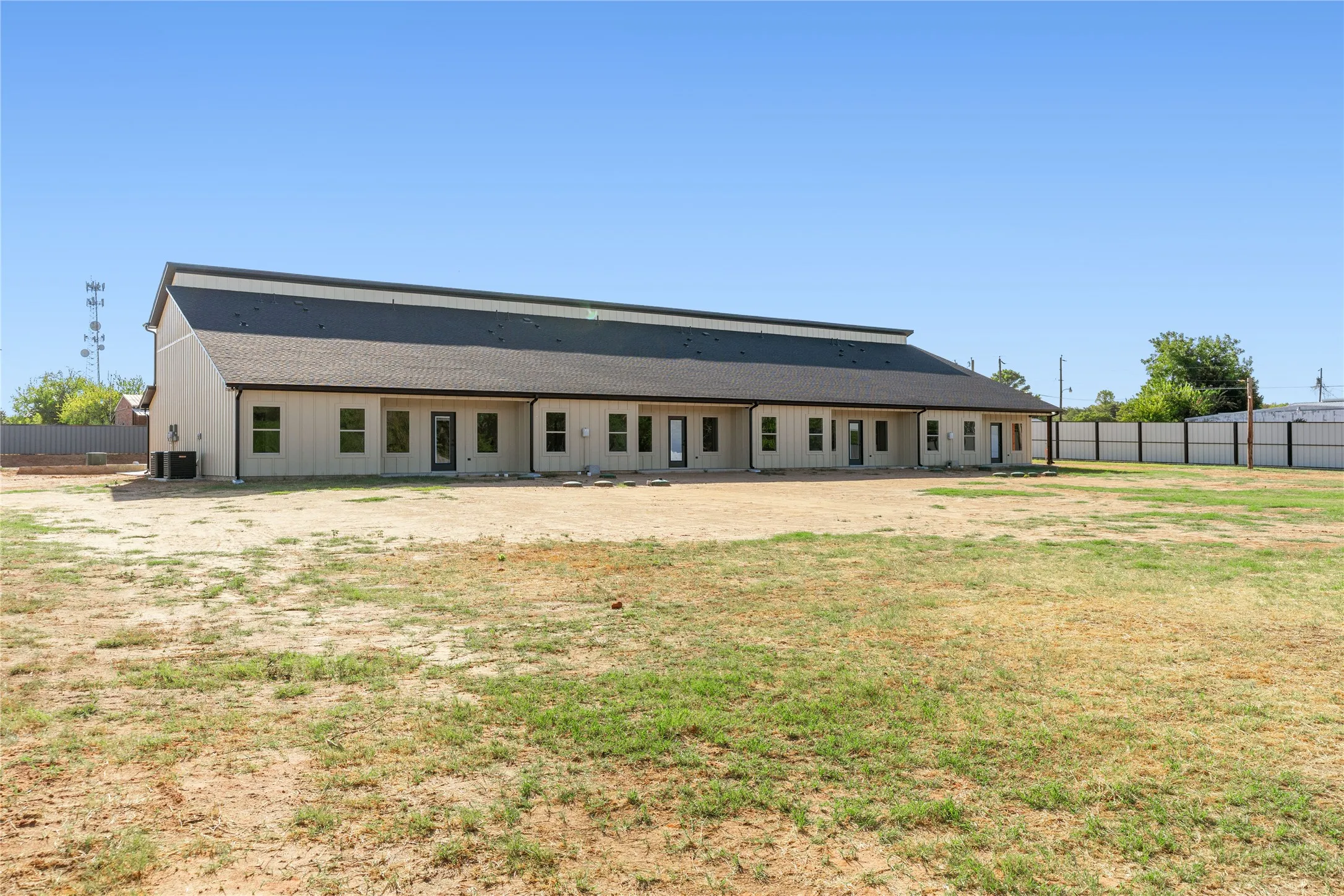 Newly constructed structure featuring vertical panel siding and a dark shingle roof