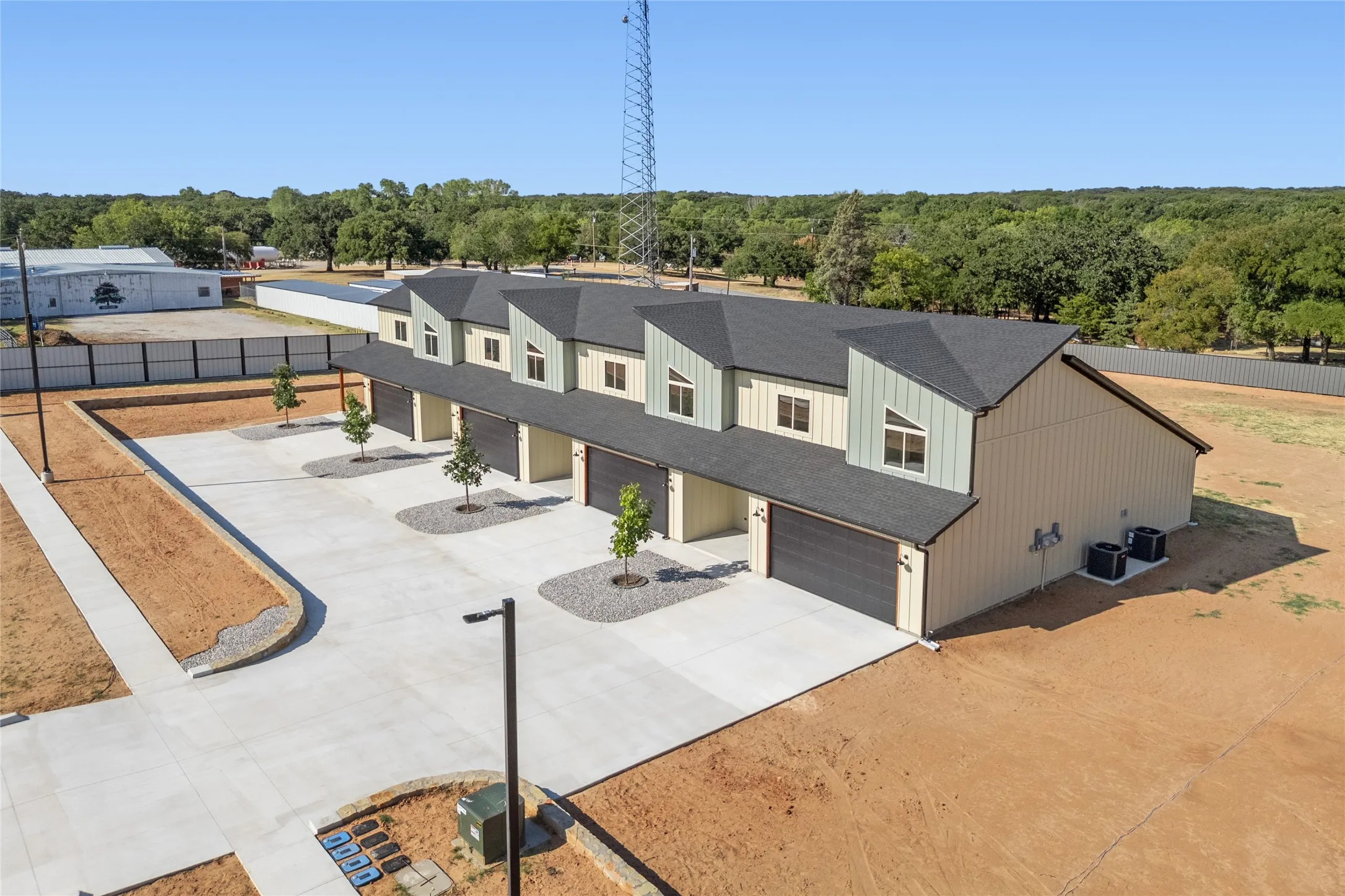 Modern multi-unit property featuring dormer windows, individual garage doors, dedicated concrete driveways, and side-mounted HVAC units