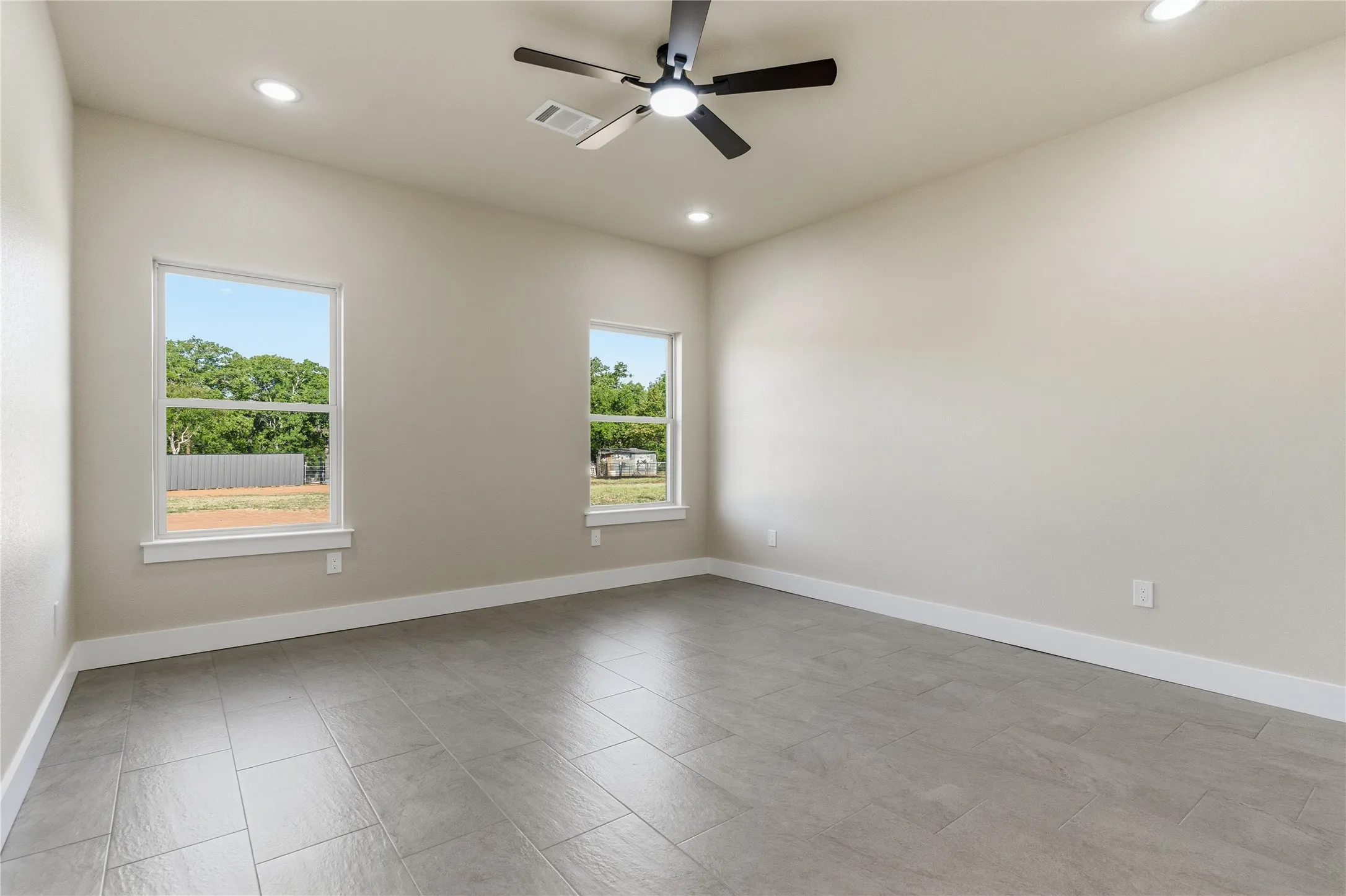 Recessed lighting, ceiling fan, two windows, and tile flooring