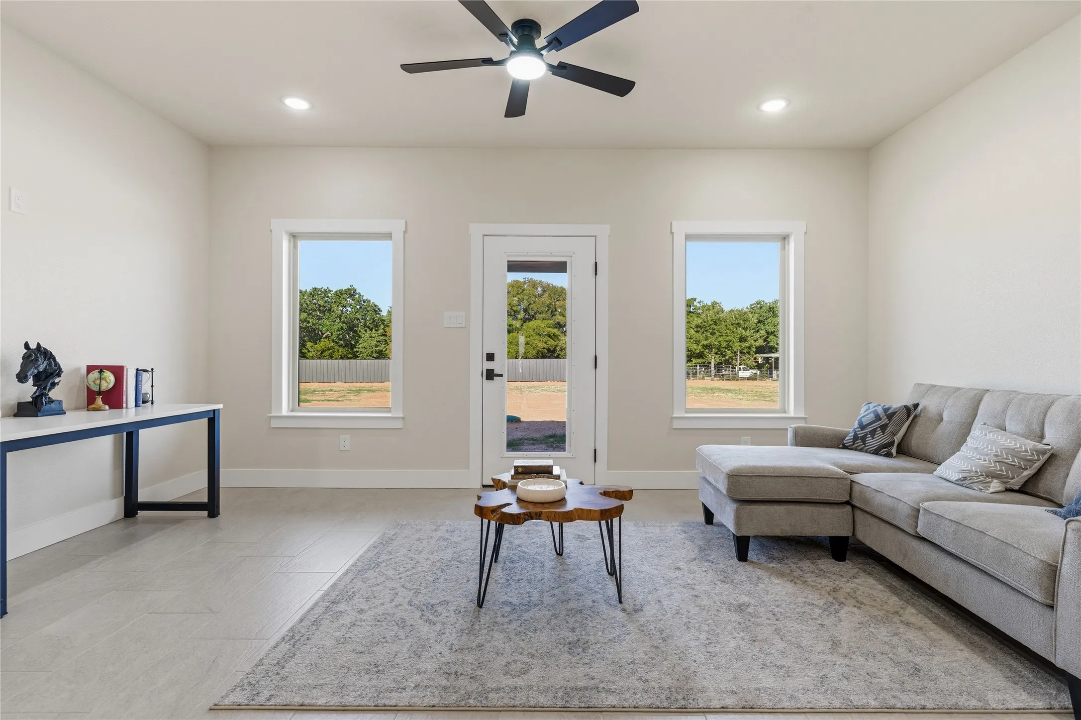 Recessed lighting, ceiling fan, ceramic tile flooring, three large windows, and a glass-paneled door