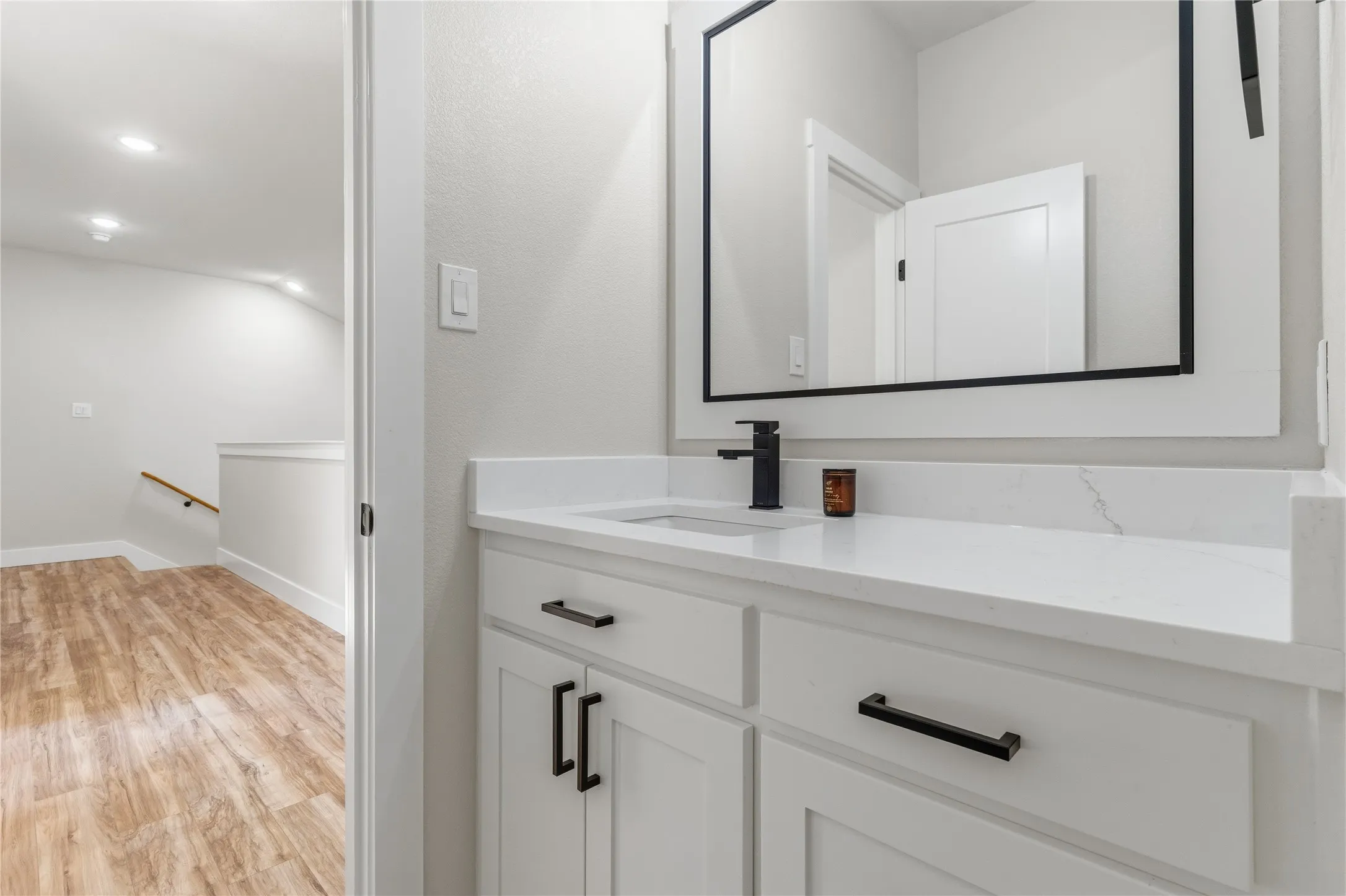 White vanity with matte black hardware, integrated sink, and stone-finish countertop