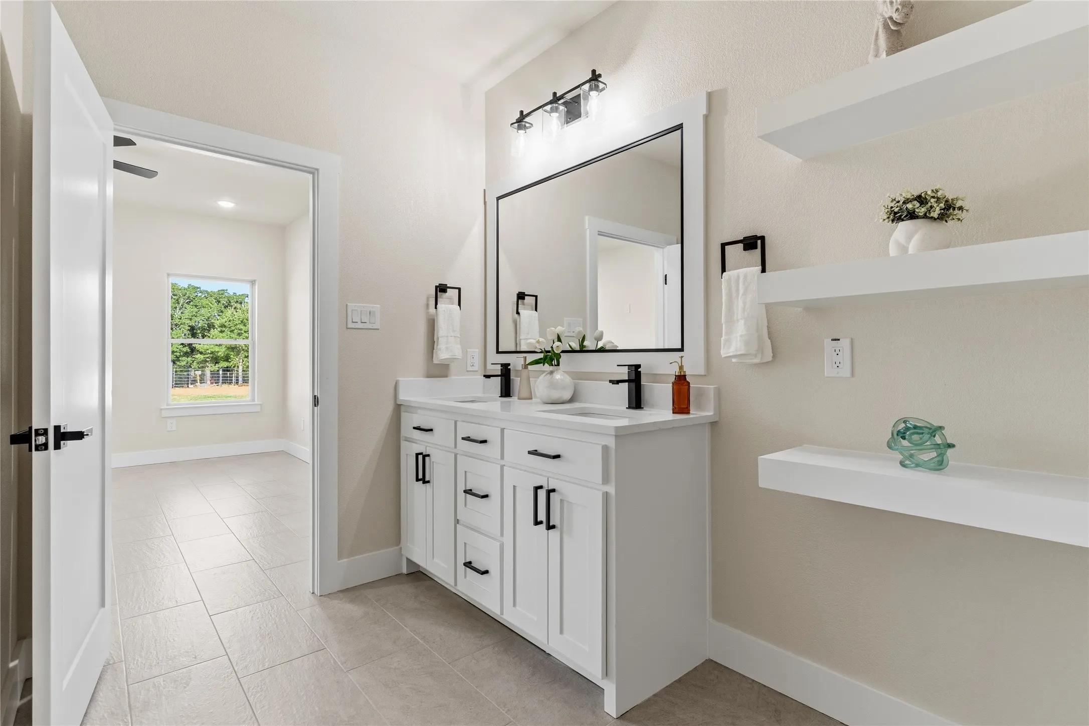 Dual vanity with white cabinetry, black hardware, and integrated sinks