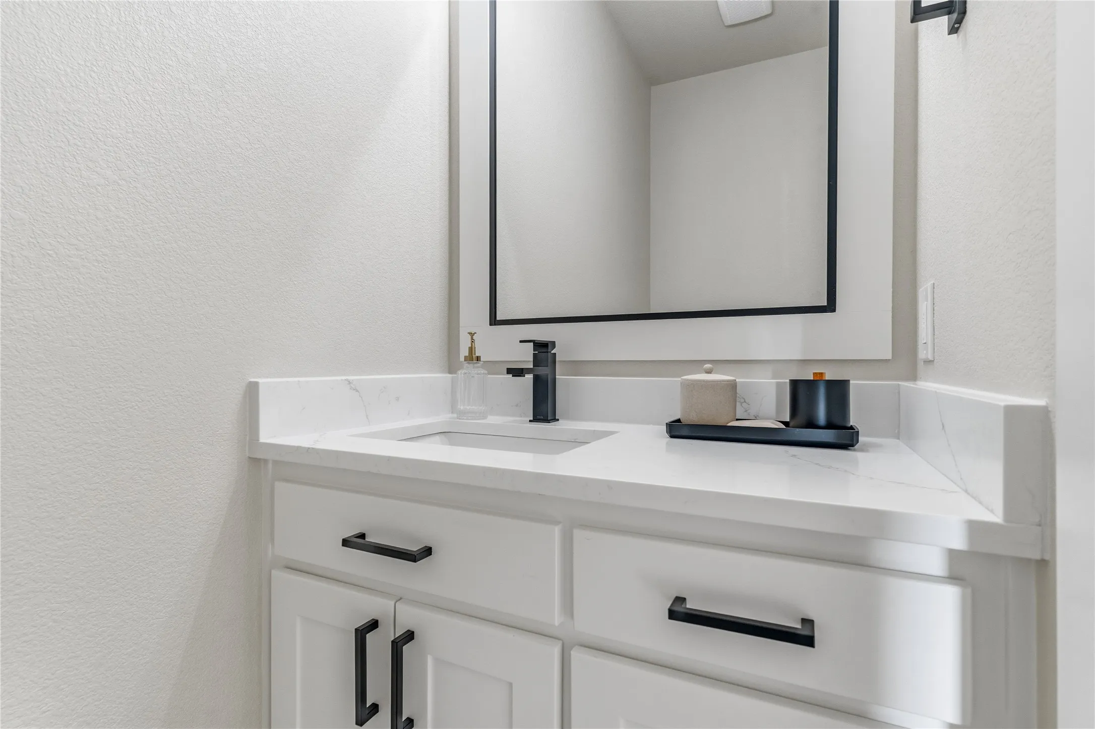 White shaker-style vanity with matte black hardware, integrated sink, and white countertop
