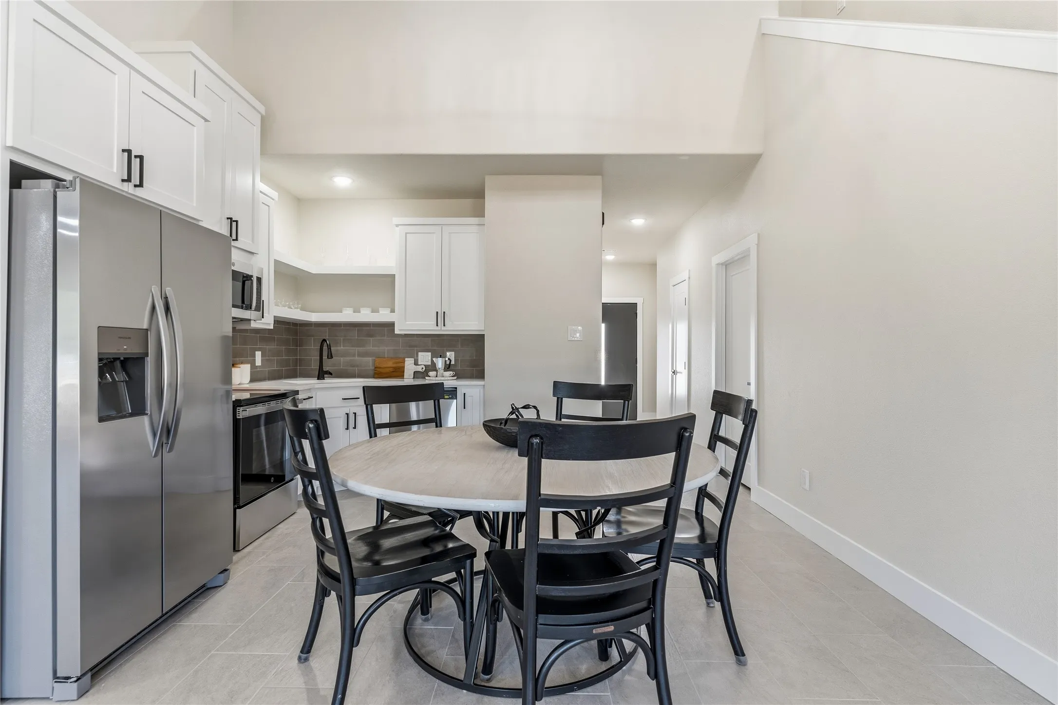 Kitchen featuring white cabinetry, stainless steel appliances, subway tile backsplash, and light-toned flooring
