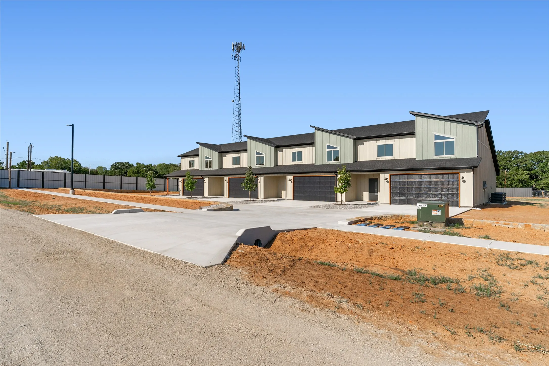 Multi-level townhomes featuring light-colored siding, dark-framed windows, and attached garages with dark doors