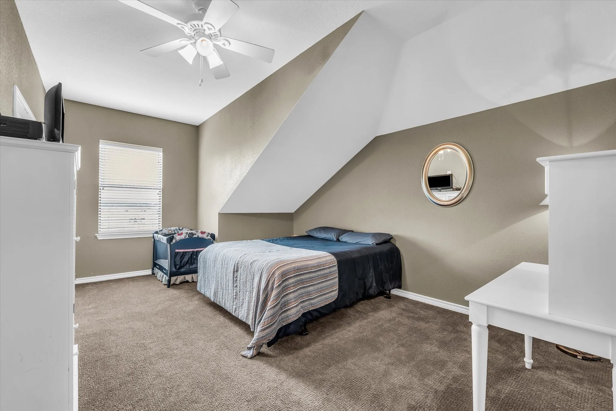 Carpeted room with a ceiling fan, window with blinds, and sloped ceiling