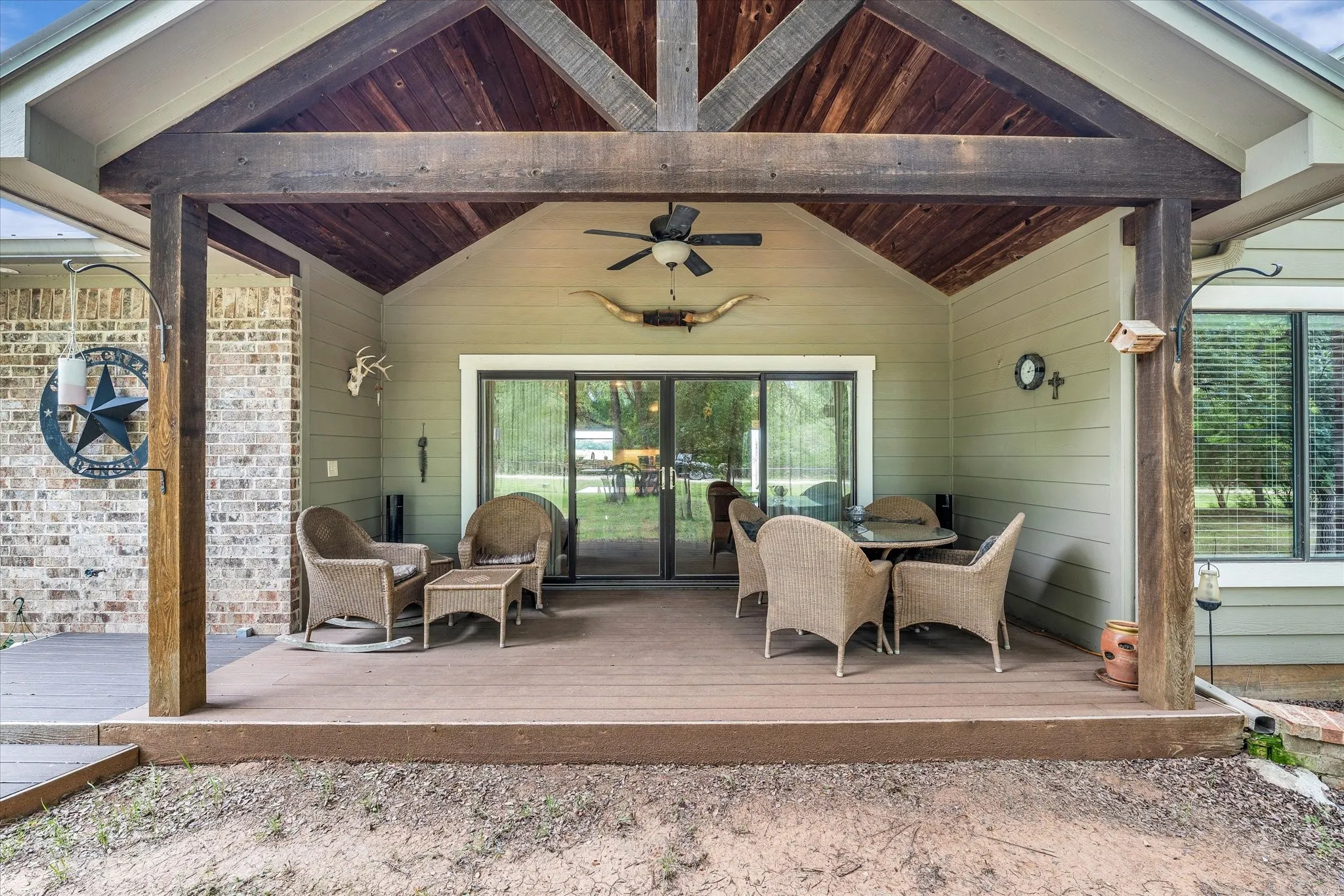 Covered outdoor patio featuring a vaulted wood-paneled ceiling, exposed wooden beams, and a ceiling fan