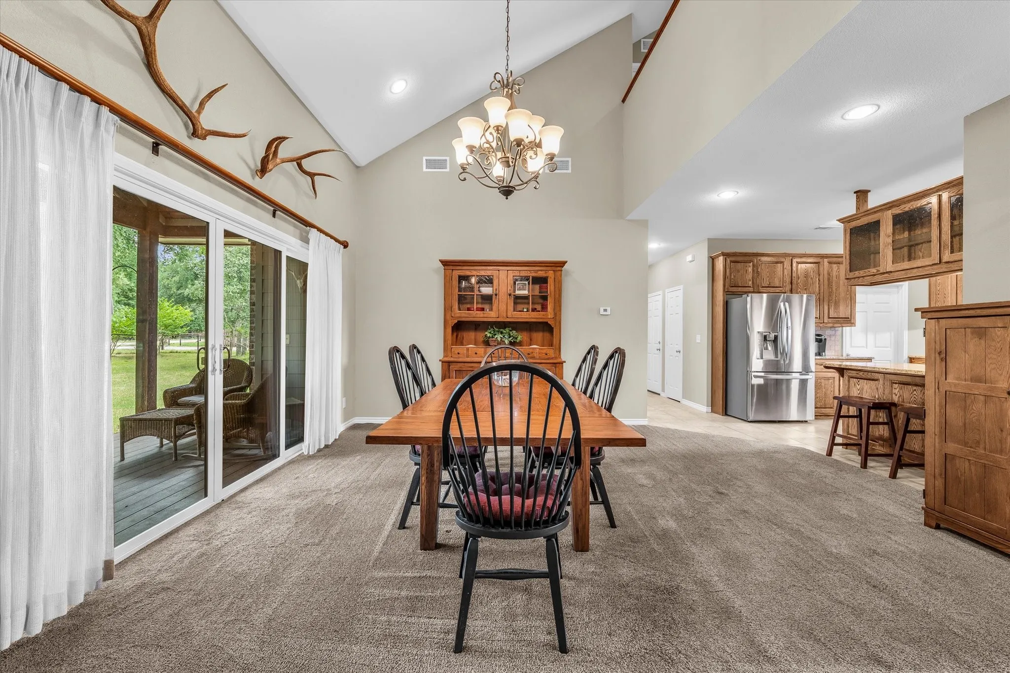 Vaulted ceiling dining area featuring a chandelier, sliding glass doors, and a neutral wall palette