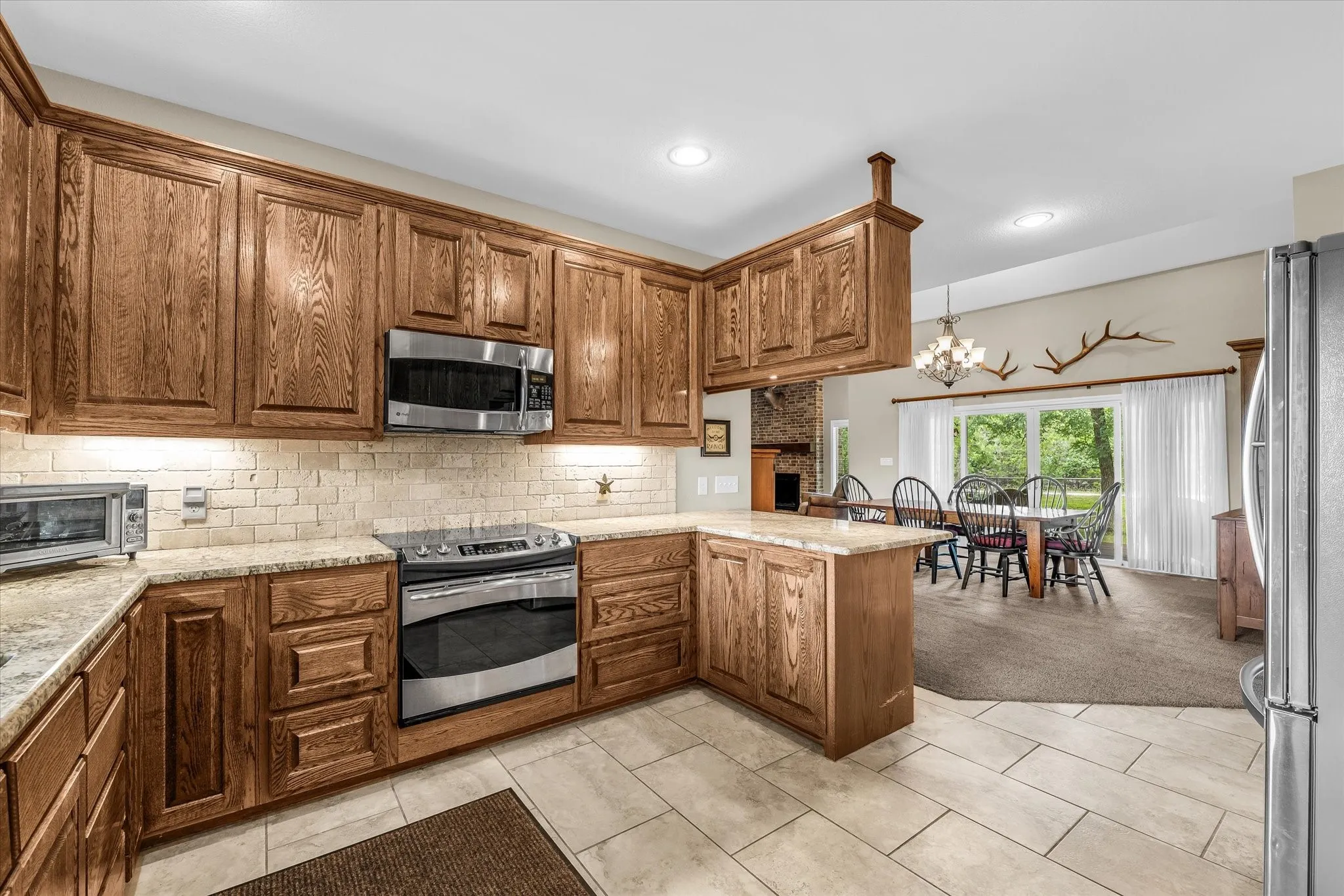 Kitchen featuring wood cabinetry, stainless steel appliances, light-toned countertops, and a subway tile backsplash