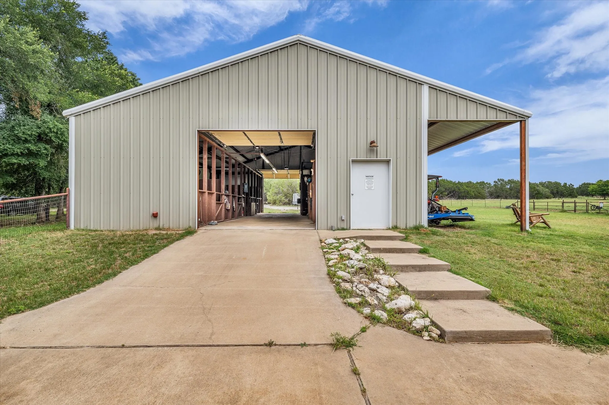 Metal-sided barn featuring an open bay entrance, side entry door, and an attached covered overhang