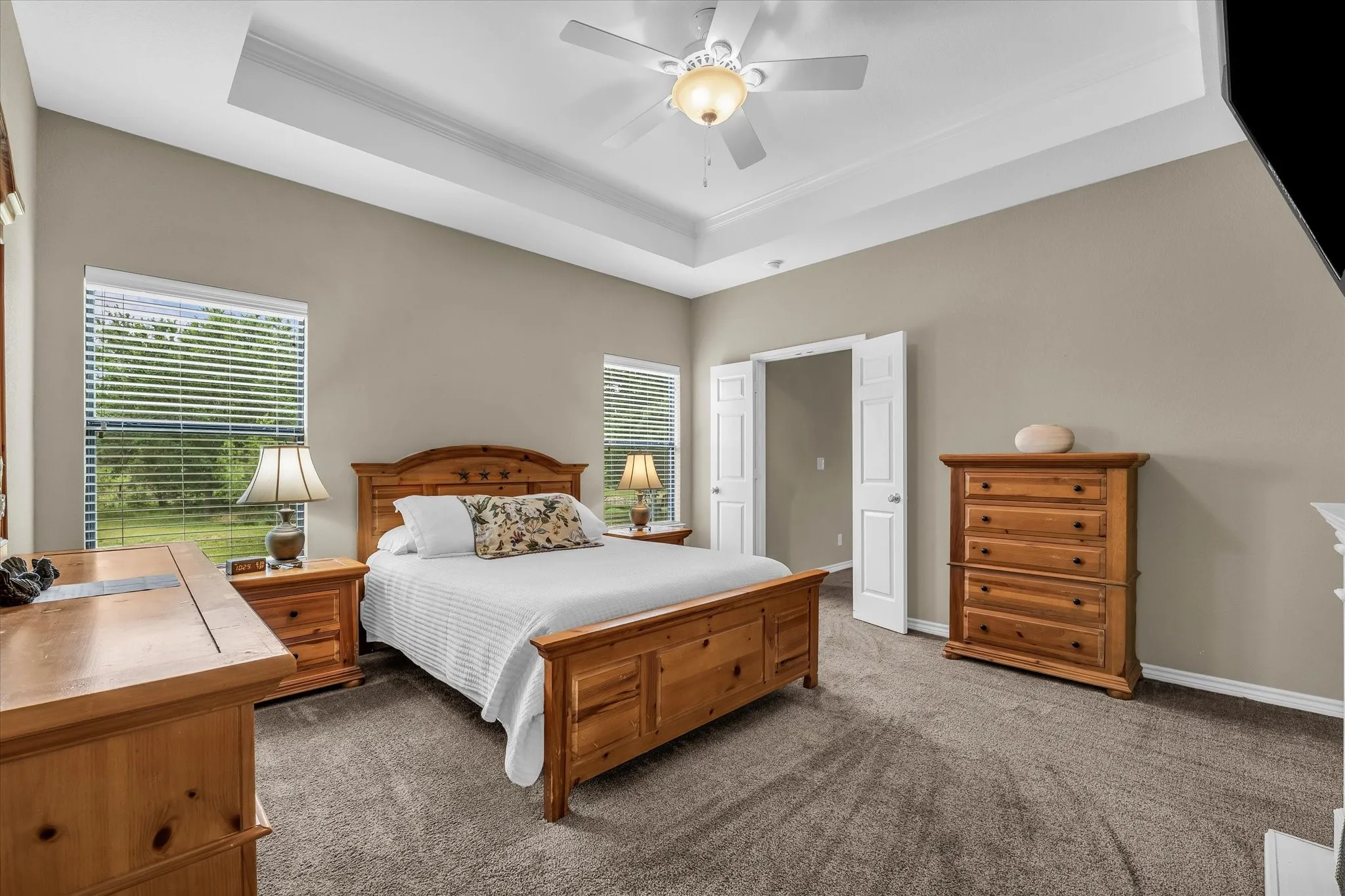 Spacious room featuring a tray ceiling with a ceiling fan, carpet flooring, and neutral wall tones