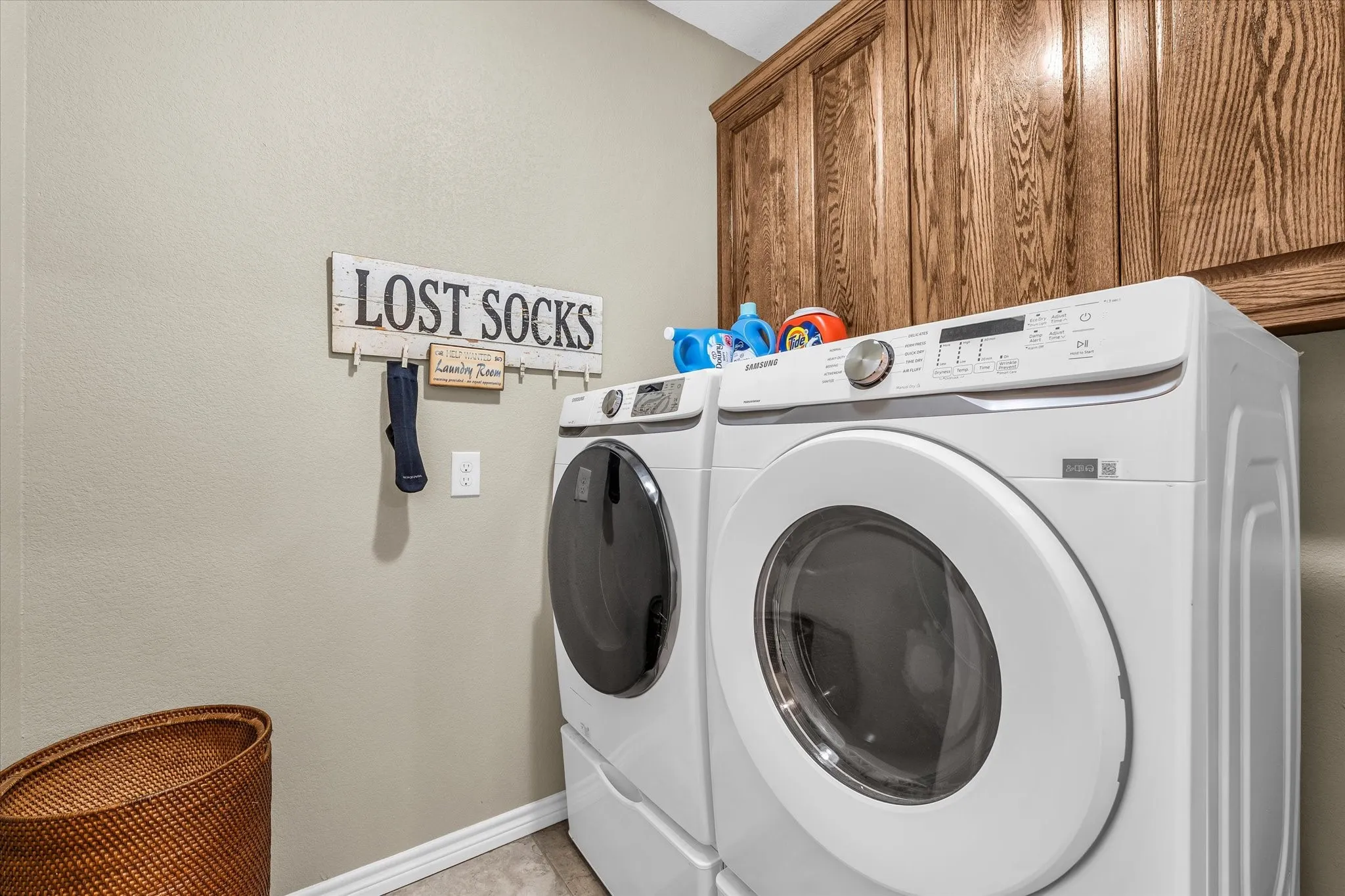 Laundry area featuring wood-finish cabinetry and light-toned walls