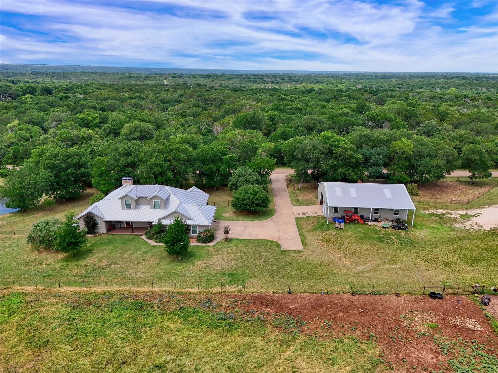 Ranch-style residence featuring a prominent metal roof, a covered front porch, and a stone chimney