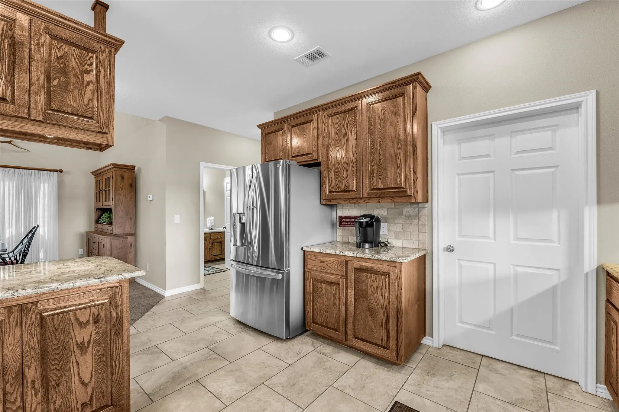 Kitchen featuring extensive wood cabinetry, granite countertops, tile flooring, and recessed lighting
