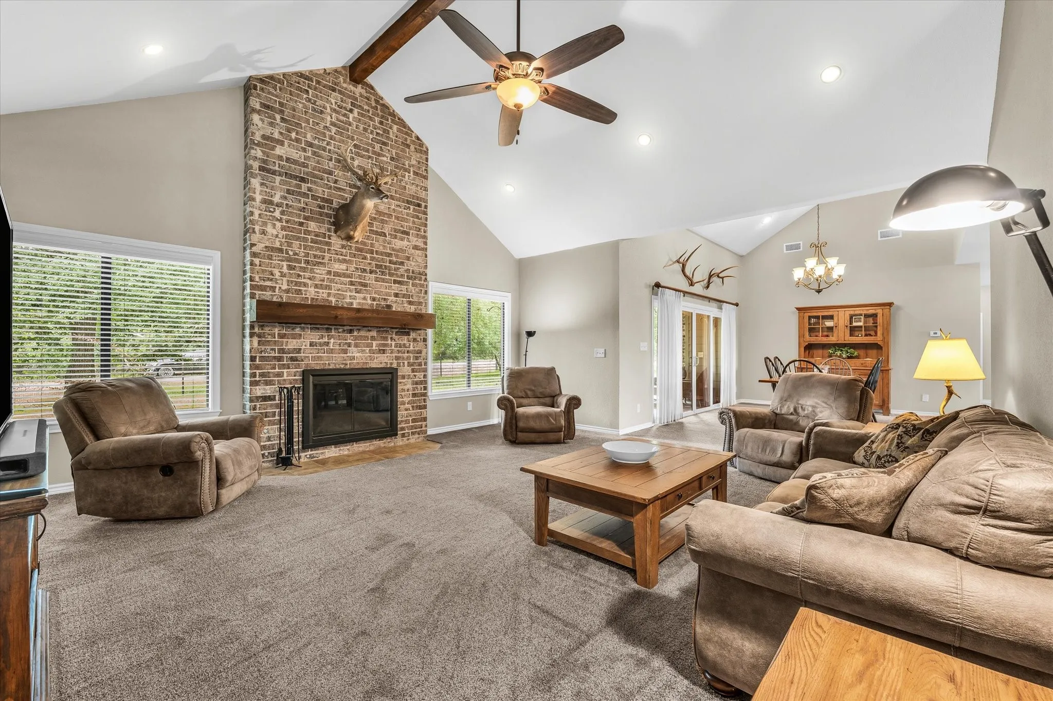 Living area featuring a floor-to-ceiling brick fireplace with a wood mantle, vaulted ceilings, recessed lighting, and a ceiling fan