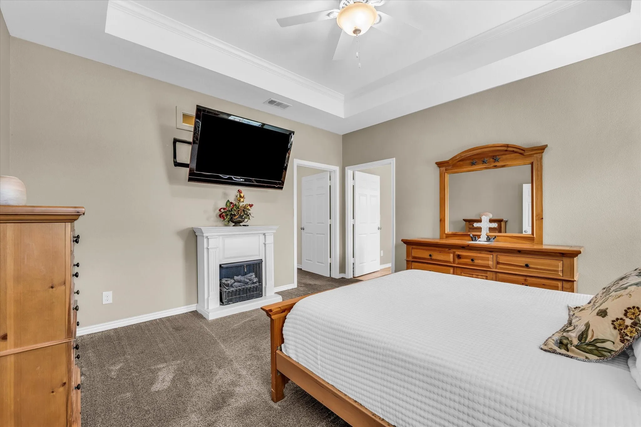 Spacious room featuring tray ceilings with crown molding, a ceiling fan with integrated lighting, and neutral-toned wall paint