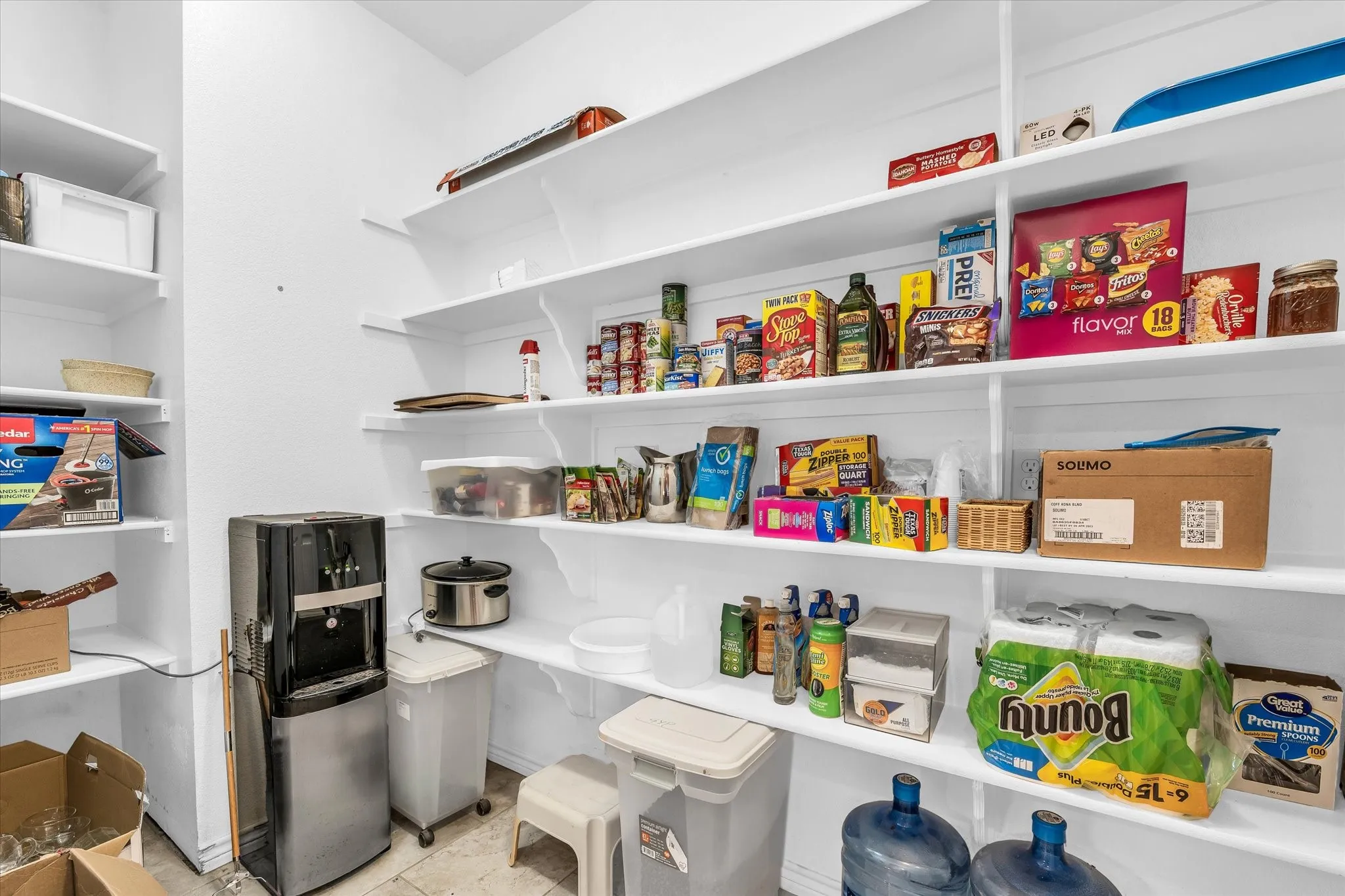Spacious pantry featuring multiple tiers of white shelving, offering extensive storage capacity