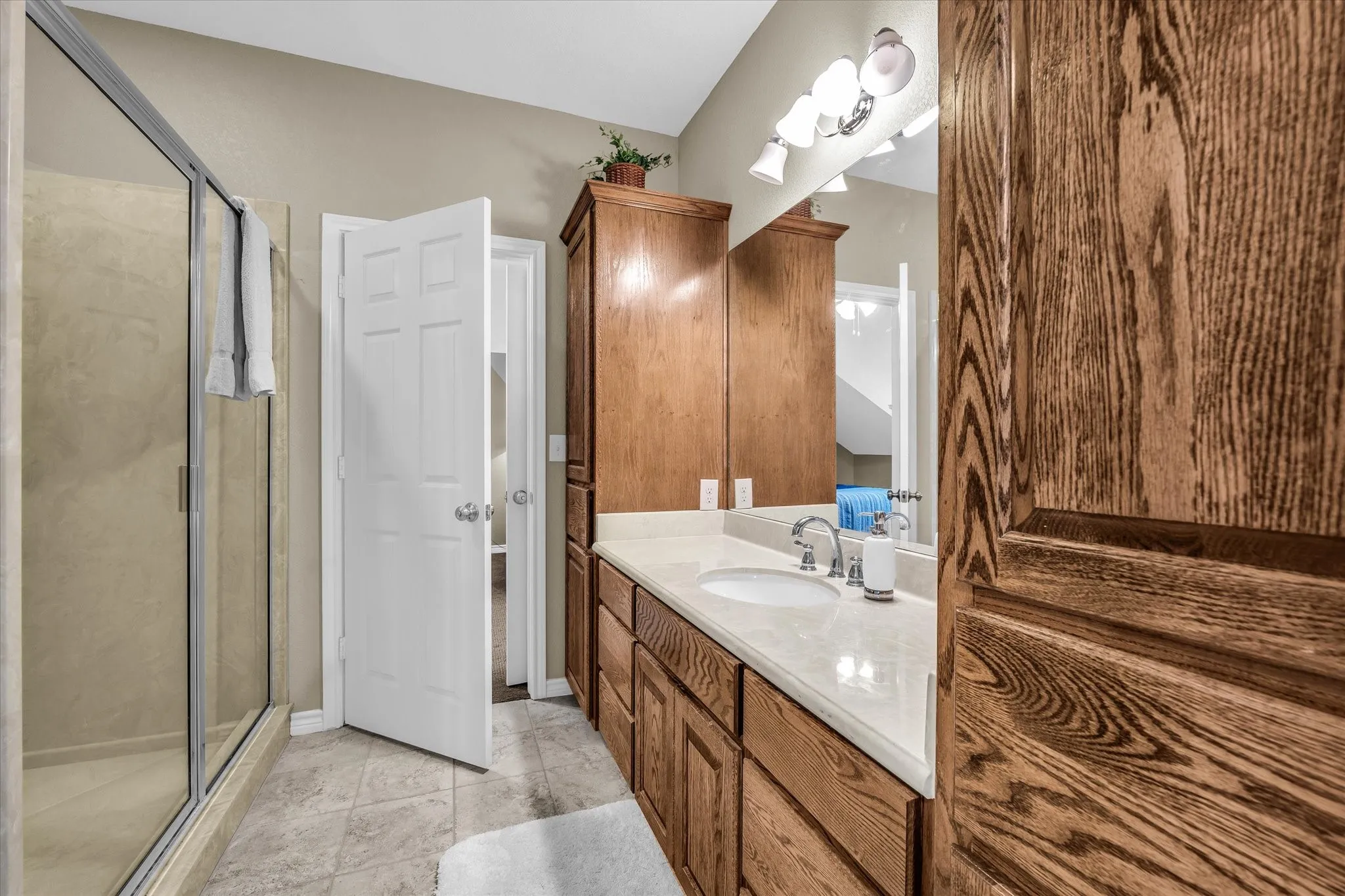 Bathroom featuring a dual vanity with light-colored countertops, wood-finish cabinetry, and a framed mirror