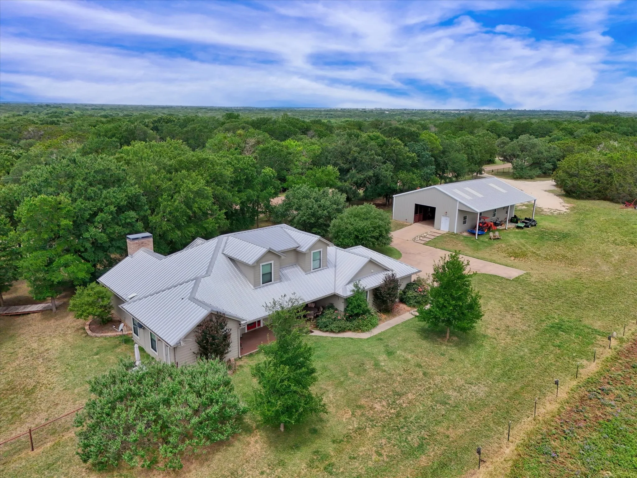 Expansive property featuring a single-story residence with a metal roof and a detached barn