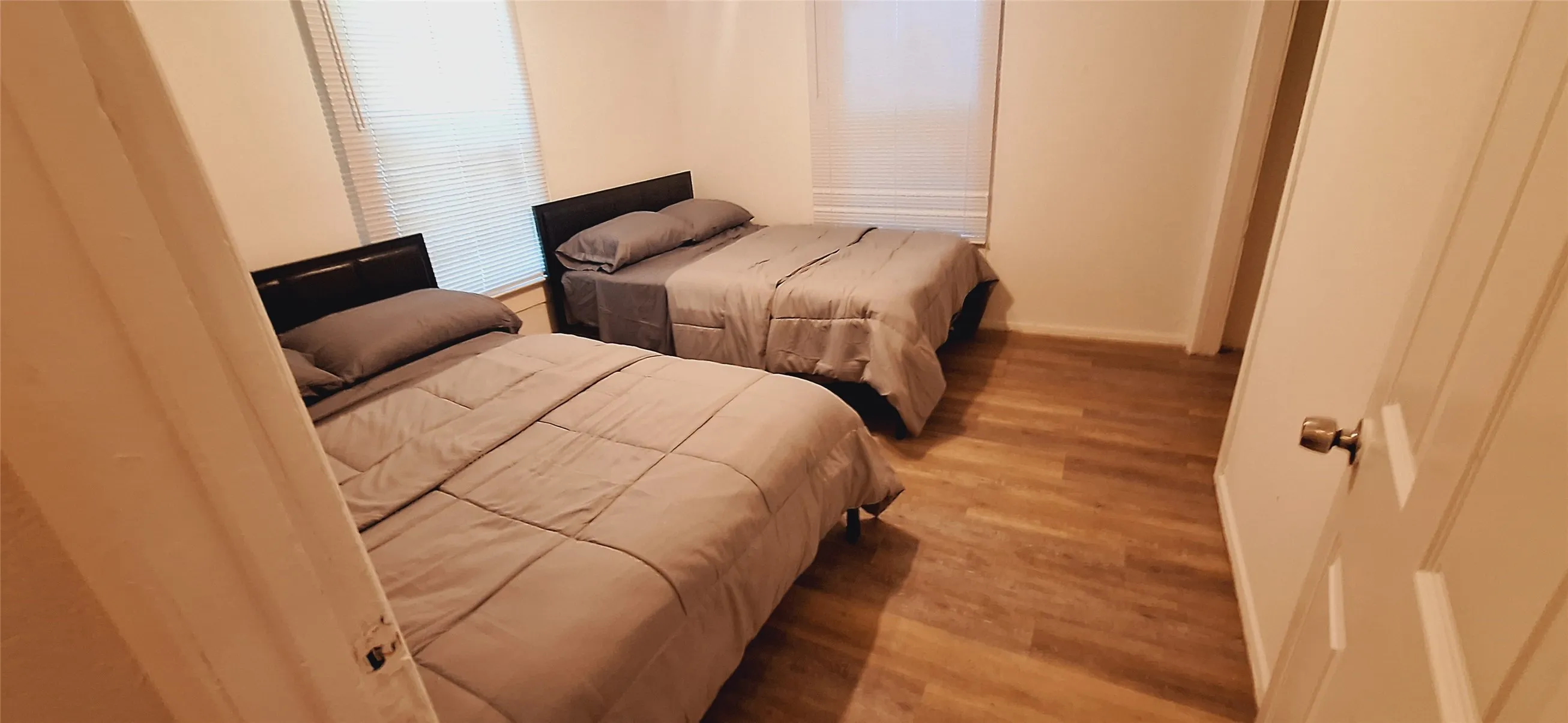 Room featuring wood-finish flooring, light neutral wall paint, and white trim
