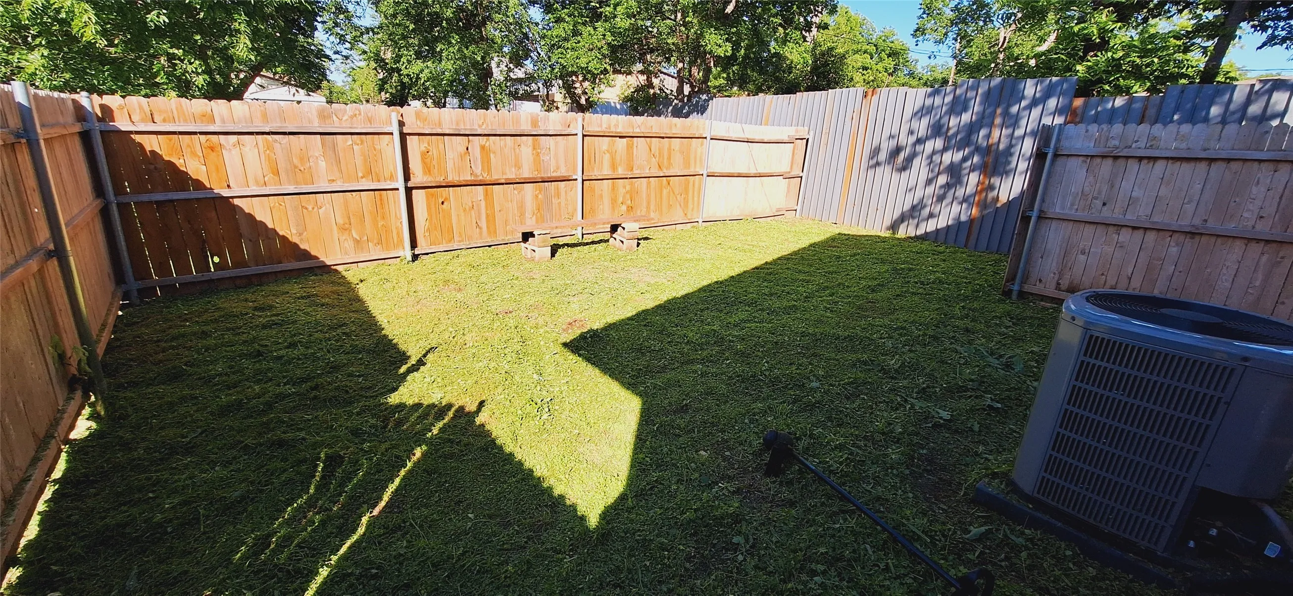 Fenced backyard with established lawn and mature perimeter trees