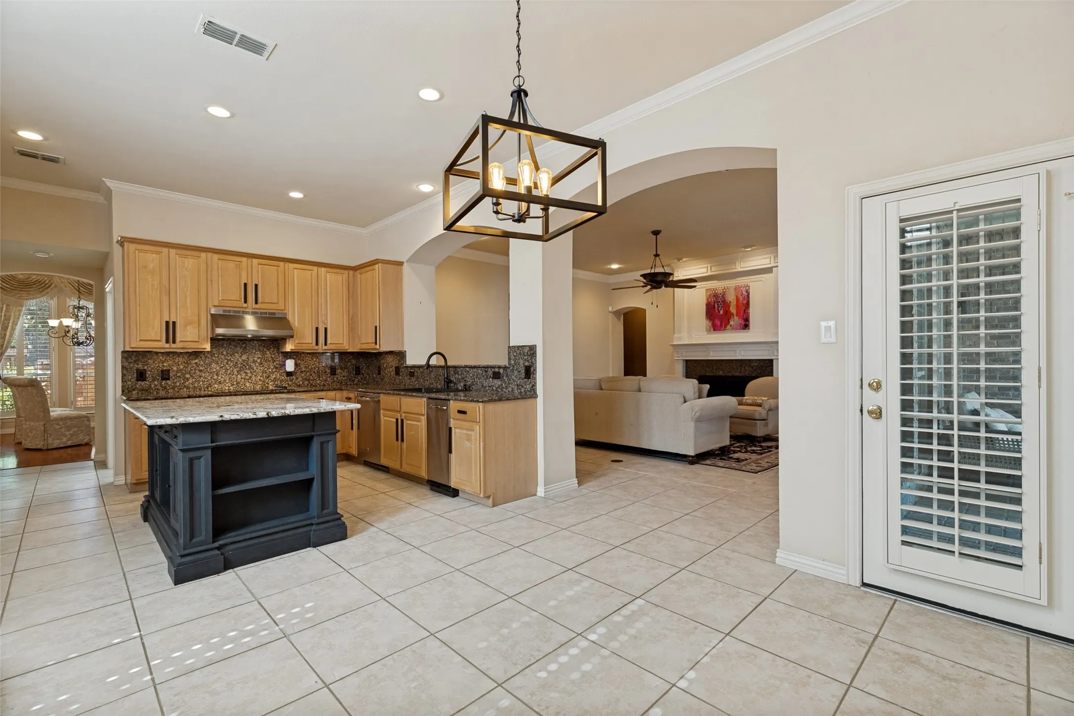 Kitchen featuring light wood cabinetry, stone countertops, stainless steel appliances, and a dark-toned island with open shelving